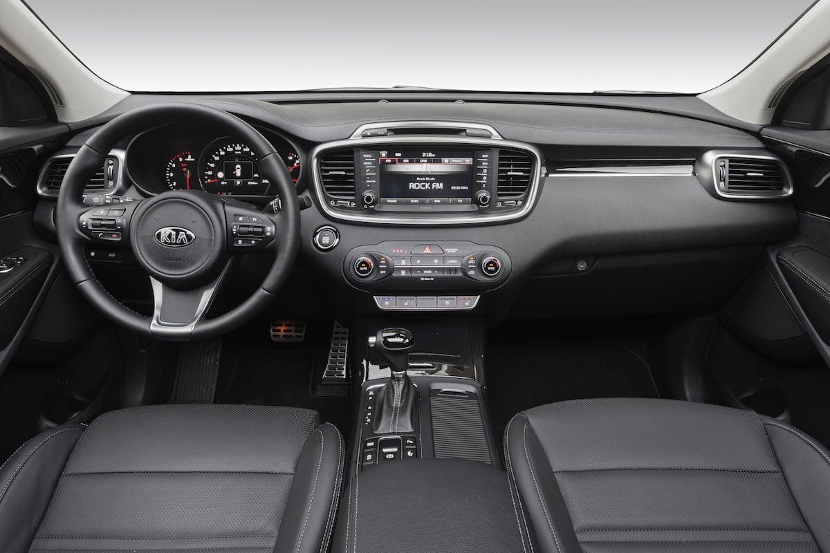 Innenraum eines Autos mit modernem Armaturenbrett, Lenkrad, Touchscreen-Display und Bedienelementen in Schwarz und Silber.