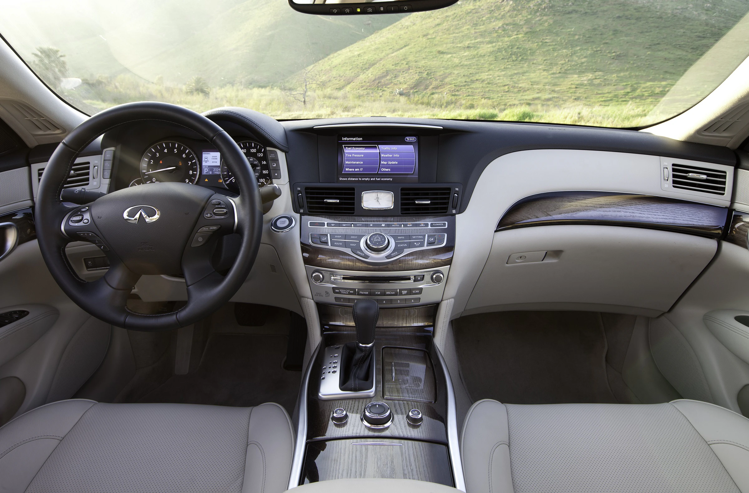 Innenraum eines Luxusautos mit Ledersitzen, Holzdetails und einem modernen Armaturenbrett mit Display und Multifunktionslenkrad.
