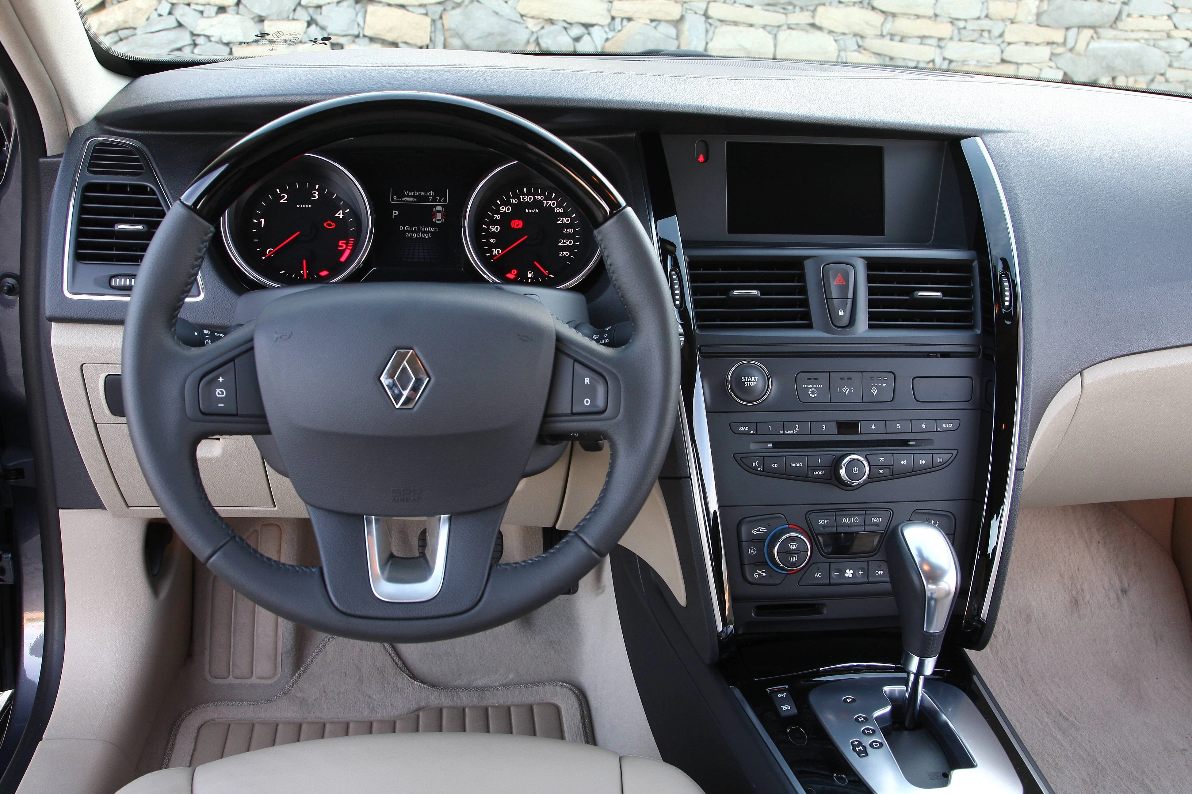 Innenraum eines Autos mit Renault-Lenkrad, zentralem Armaturenbrett mit Tachoanzeigen, Mittelkonsole und Automatikgetriebe.