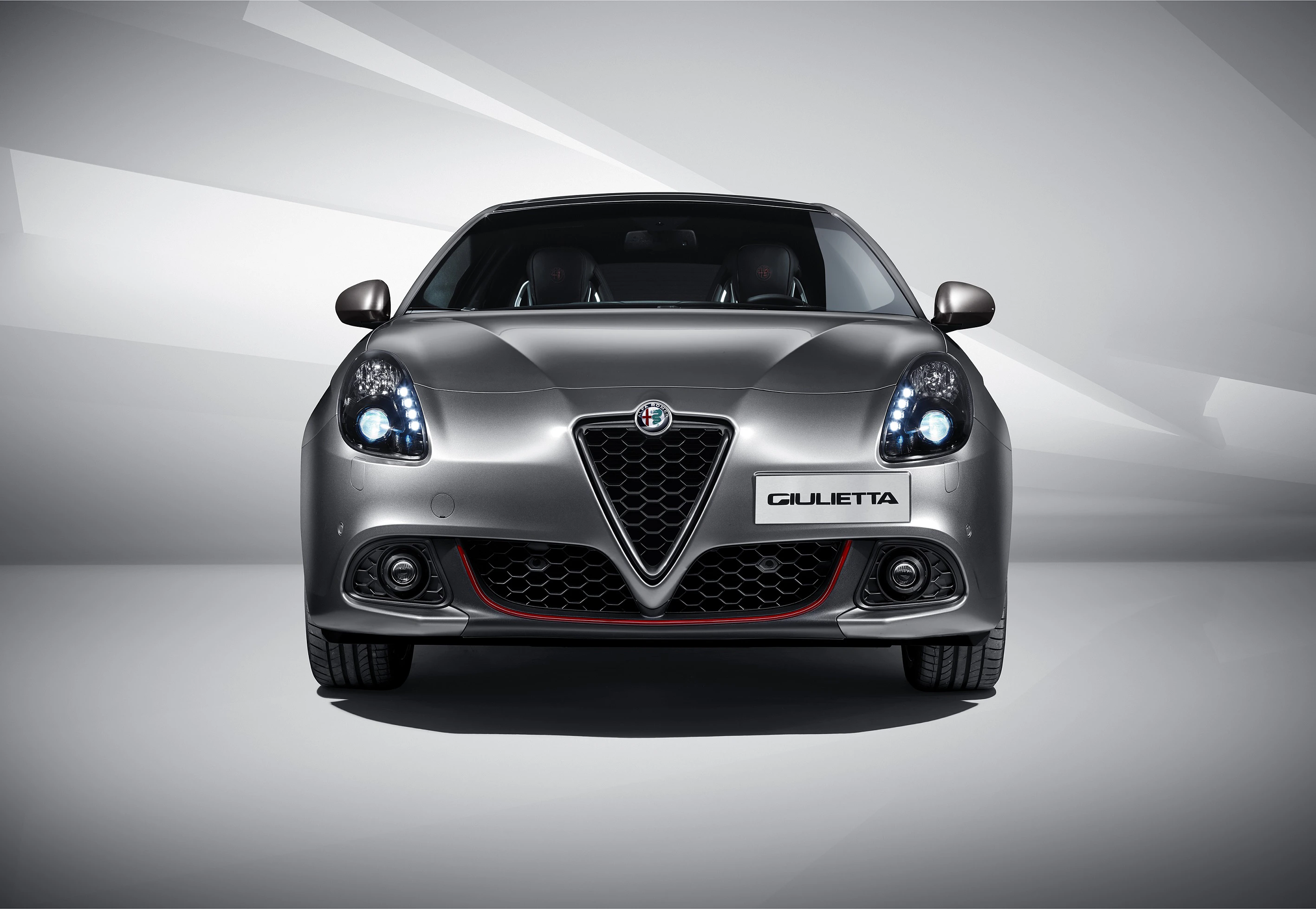 Silberner Alfa Romeo Giulietta von vorne, mit markantem Kühlergrill und dynamischem Design, vor neutralem Hintergrund.