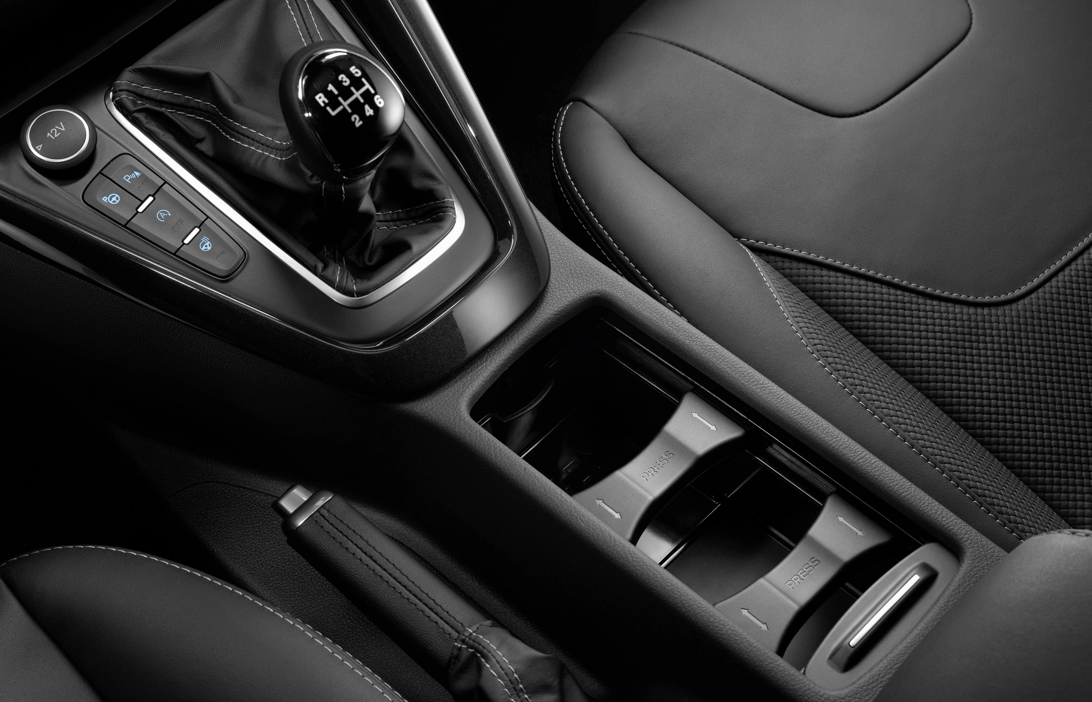 Nahaufnahme eines Autoinnenraums mit Handschaltung, Getränkehaltern und einer Handbremse in eleganten schwarzen Materialien.