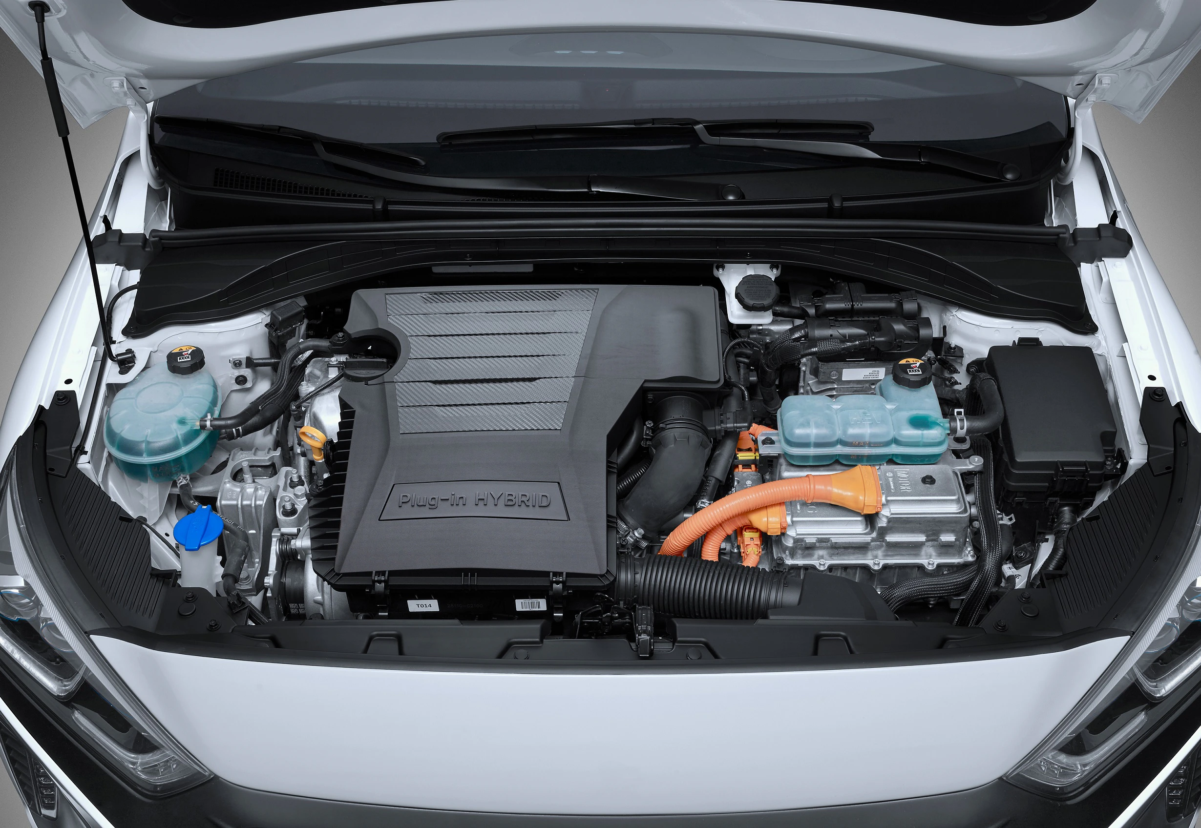 Motorraum eines Hybridautos mit sichtbarem Elektromotor, Verkabelung und Motorabdeckung in Schwarz und Grau.