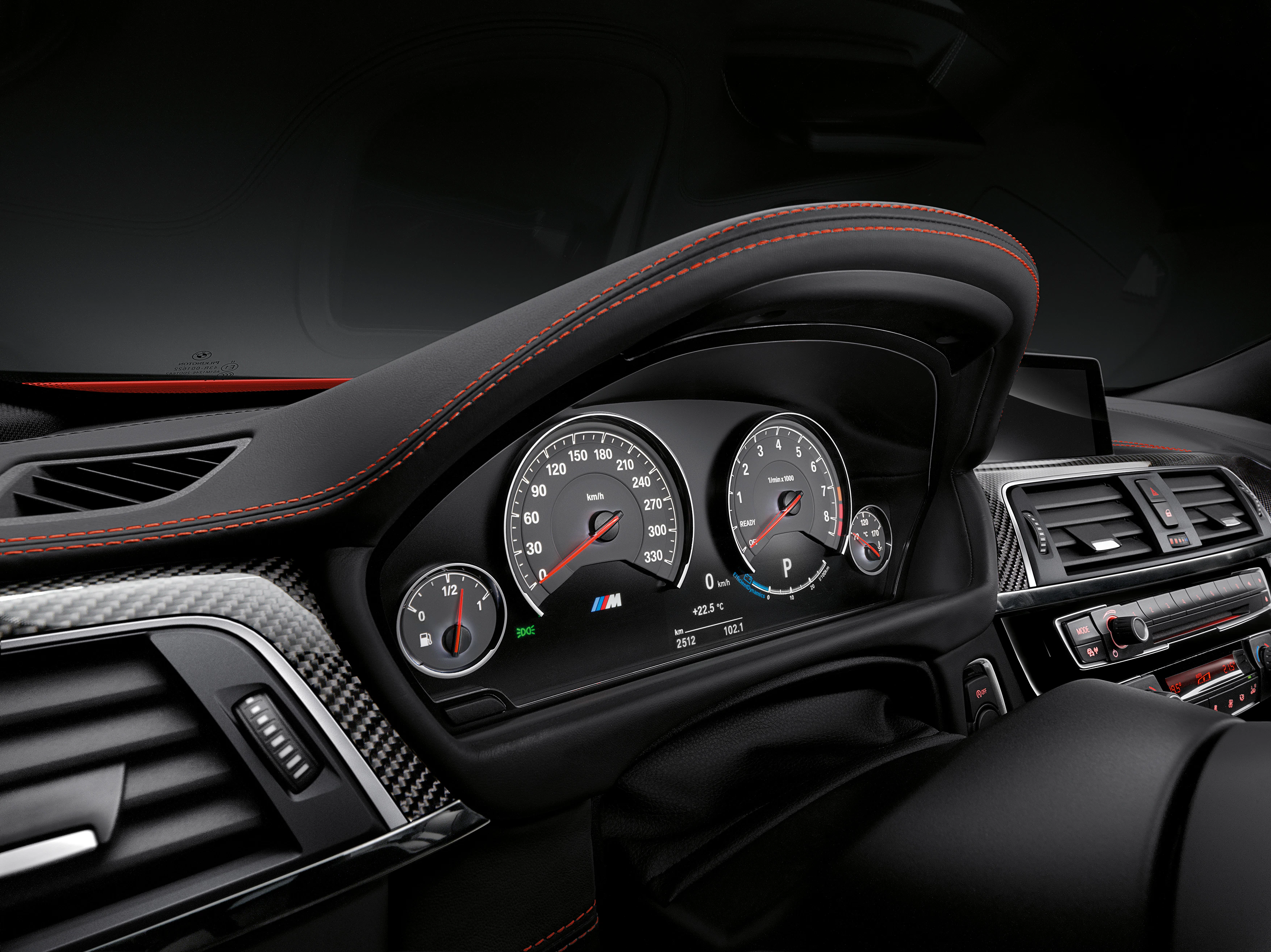 Armaturenbrett eines Autos mit Tachometer, Drehzahlmesser und roten Ziernähten. Sportliches Design mit Kohlefaser-Details.
