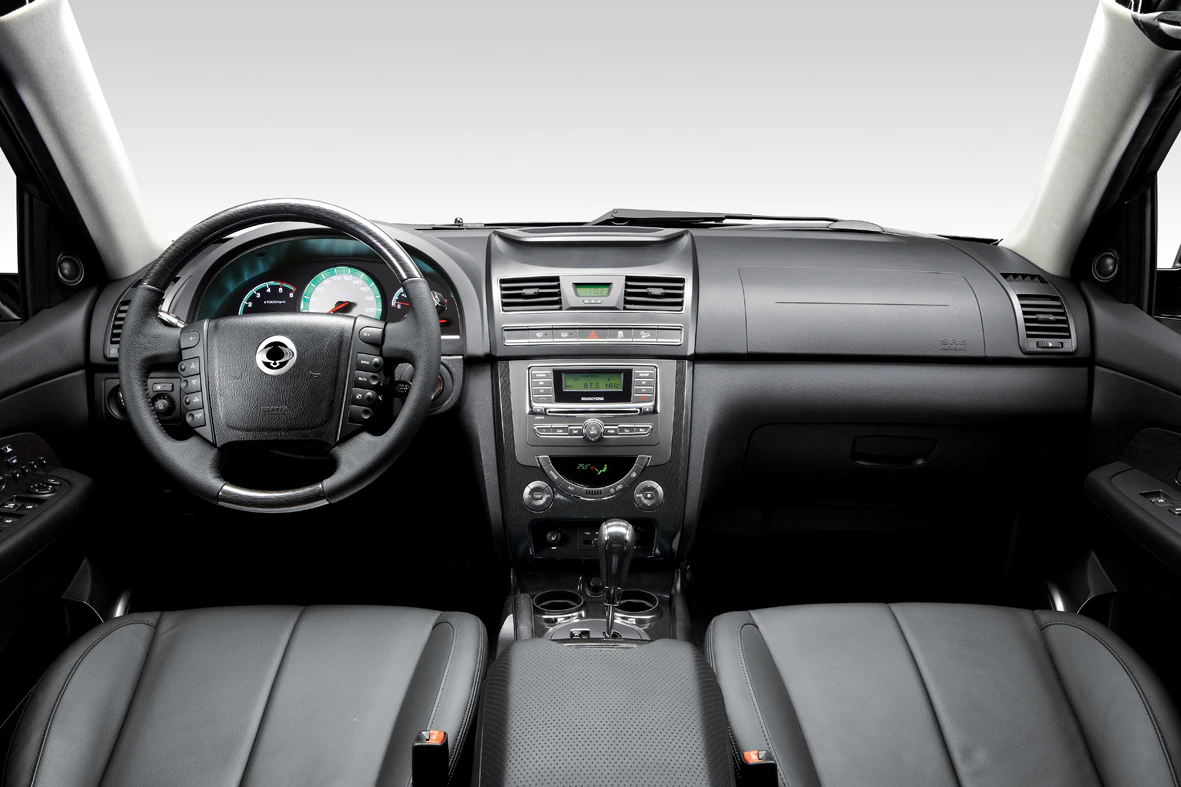 Innenraum eines Autos mit Ledersitzen, Lenkrad links, Armaturenbrett mit Display und Bedienelementen. Moderne, schlichte Gestaltung.