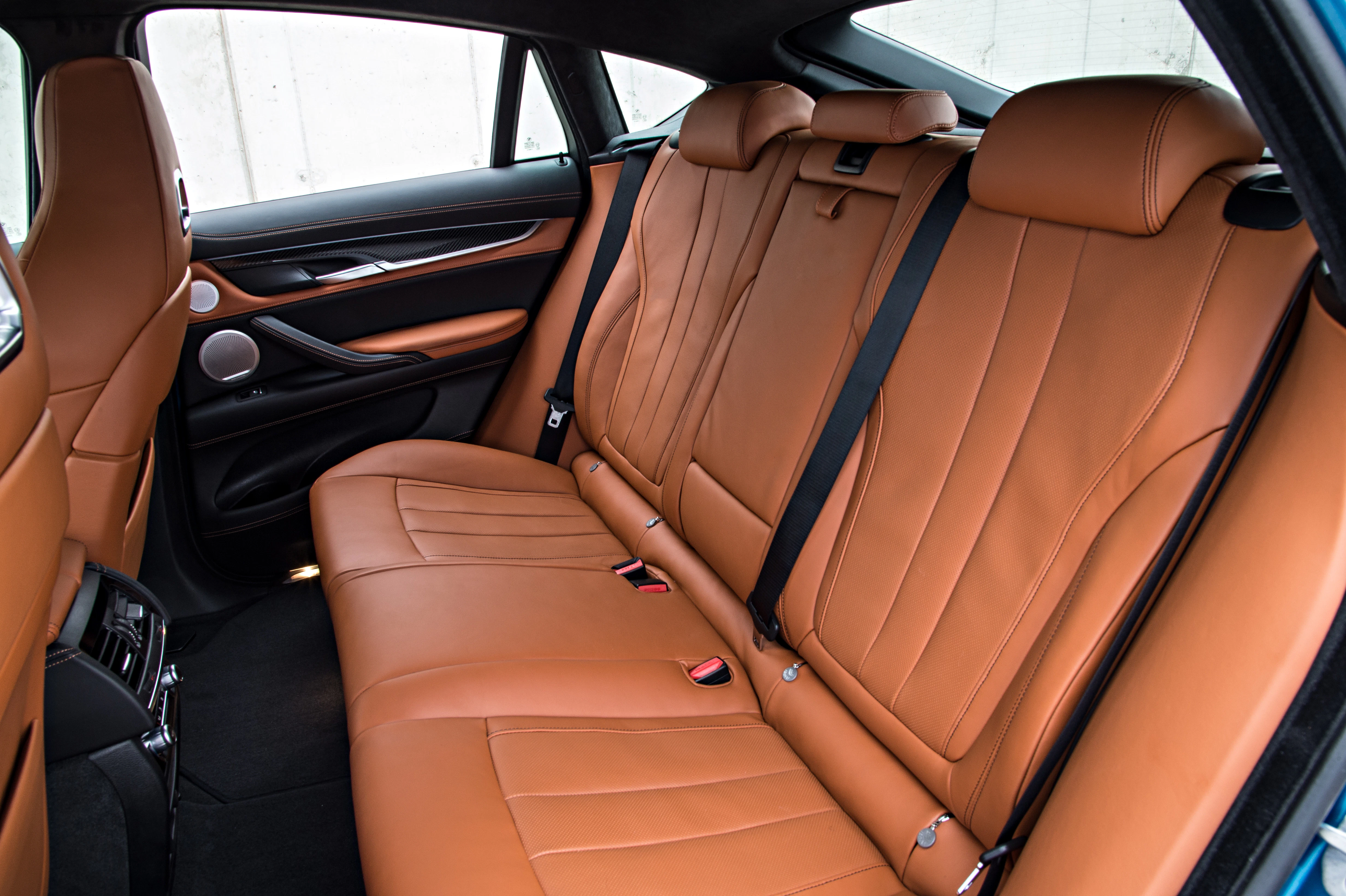 Rückansicht eines Autos mit luxuriösen, braunen Ledersitzen. Hochwertiges Interieur-Design mit Sicherheitsgurten und schwarzen Details.
