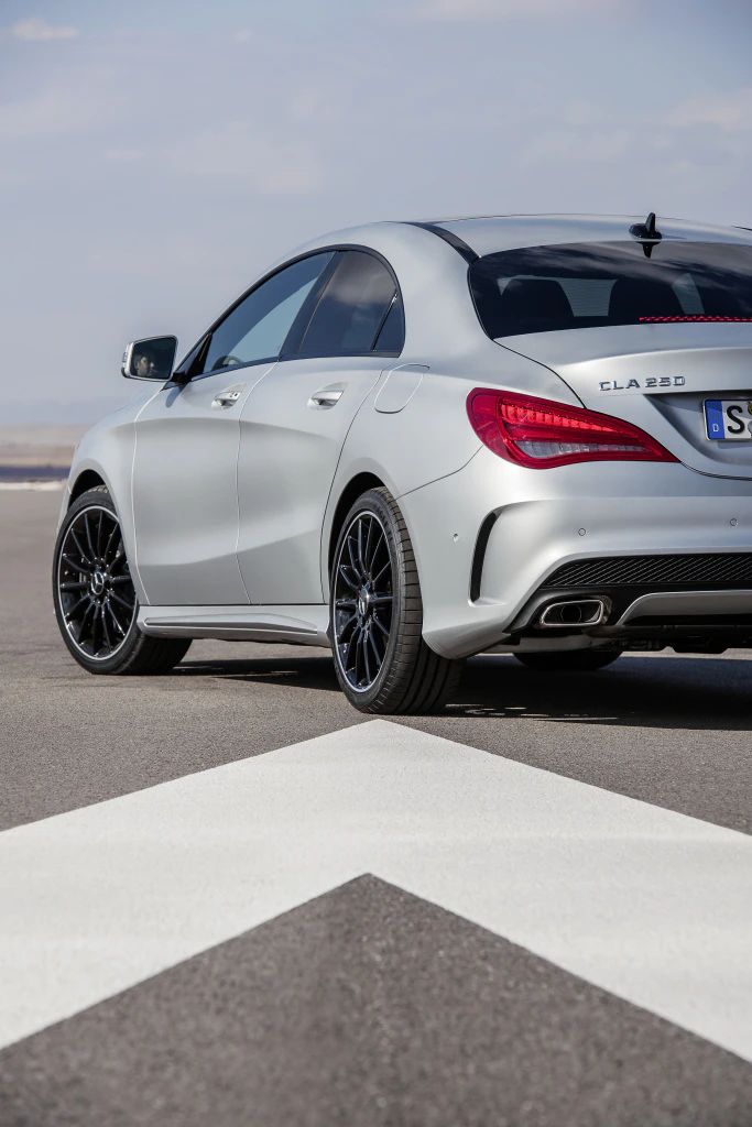 Silberner Mercedes-Benz CLA 250 auf einer Straße, seitliche Heckansicht, markante Rücklichter und schwarzer Dachbereich erkennbar.