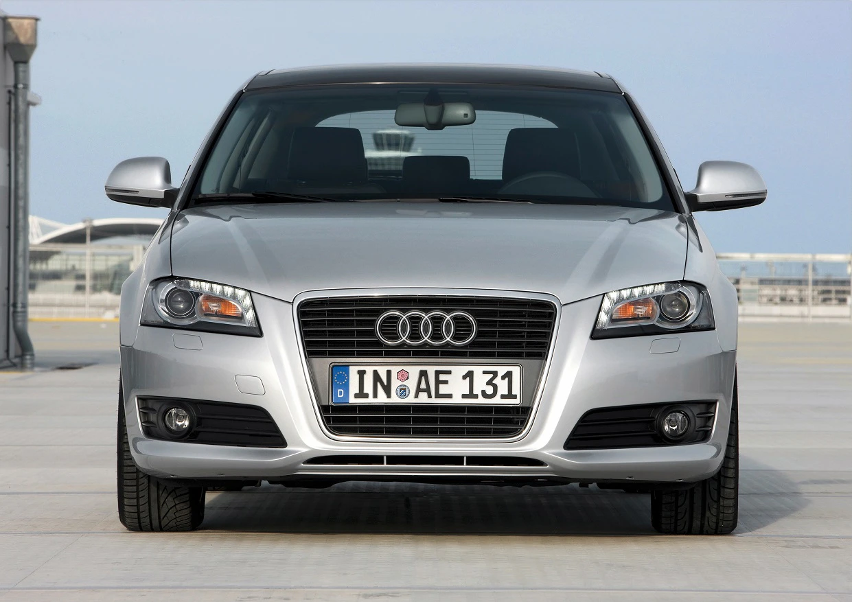 Silberner Audi A3 mit deutschem Kennzeichen, frontalansicht, auf freiem Platz bei klarem Himmel geparkt.