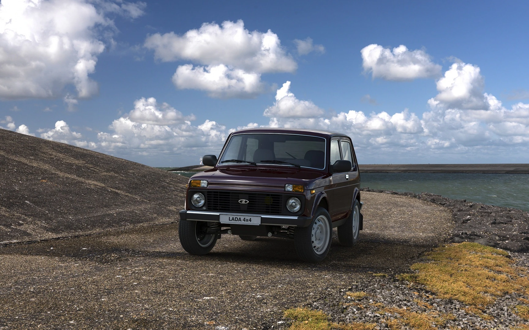Ein roter Lada 4x4 steht auf einem Küstenweg mit bewölktem Himmel und Meer im Hintergrund.