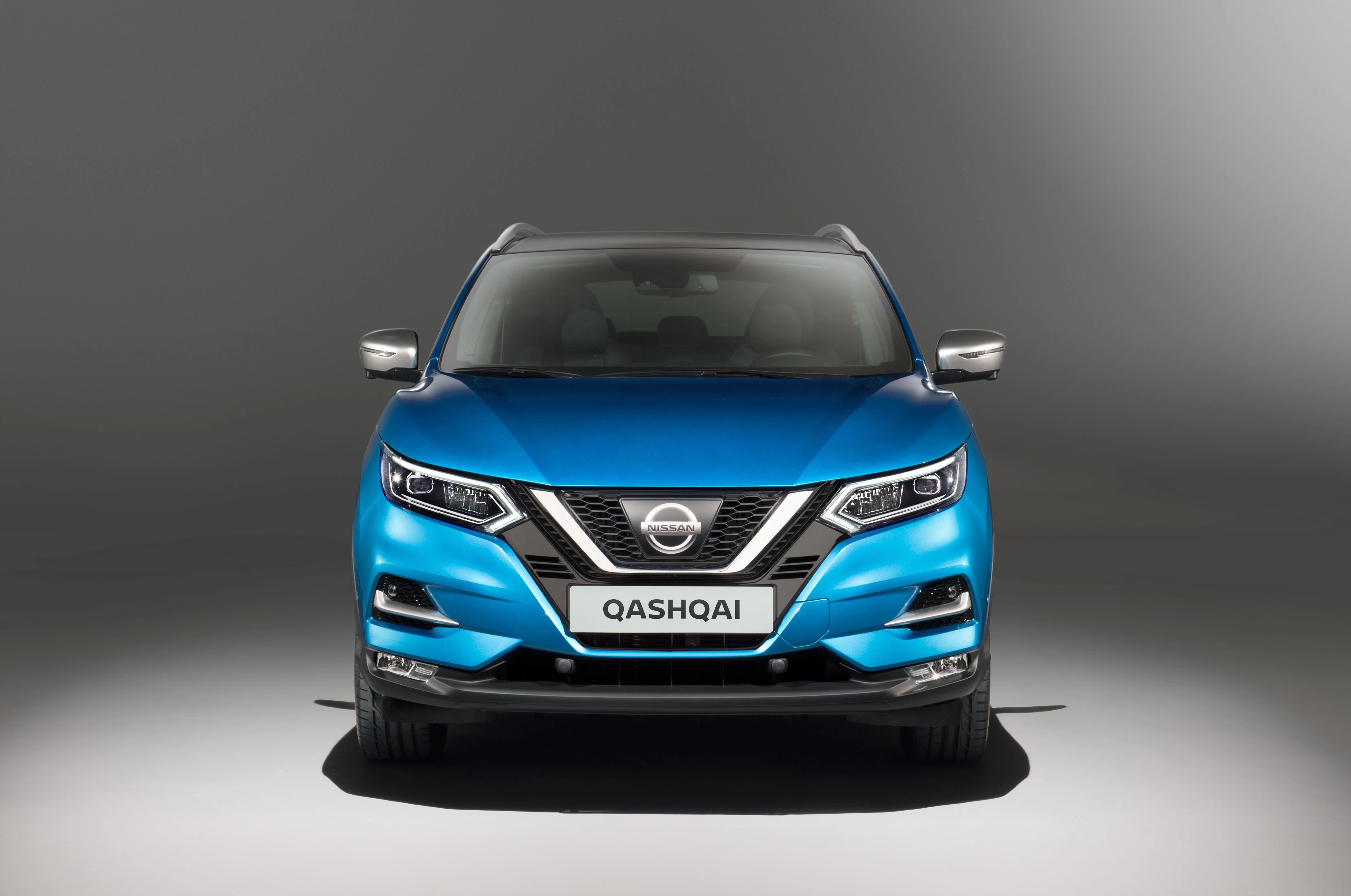 Blauer Nissan Qashqai SUV, frontal fotografiert, vor grauem Hintergrund.