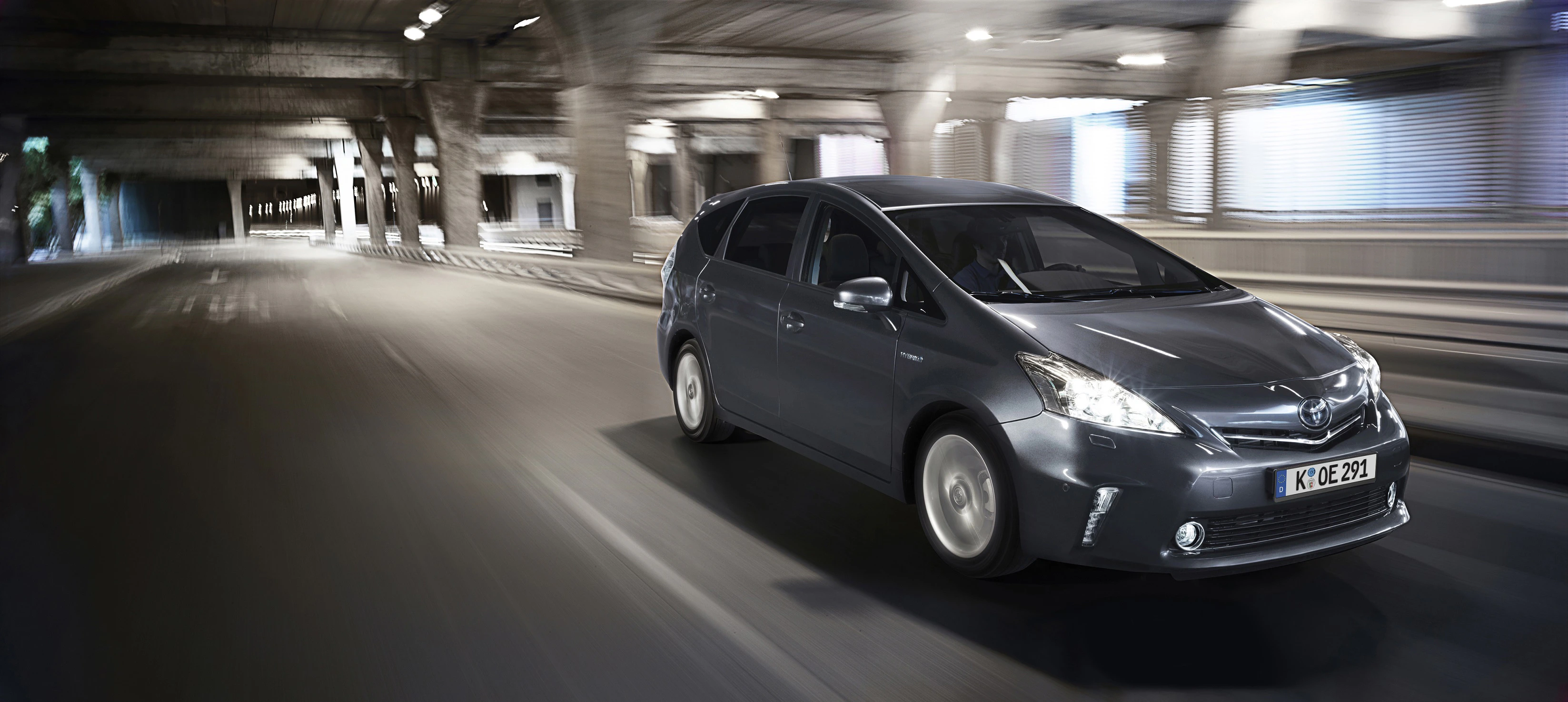 Silbernes Auto fährt schnell durch einen beleuchteten Tunnel. Dynamische Umgebung und verschwommene Hintergründe betonen die Bewegung.