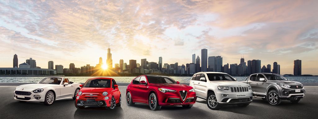 Fünf Autos verschiedener Marken nebeneinander vor einer Skyline bei Sonnenuntergang.