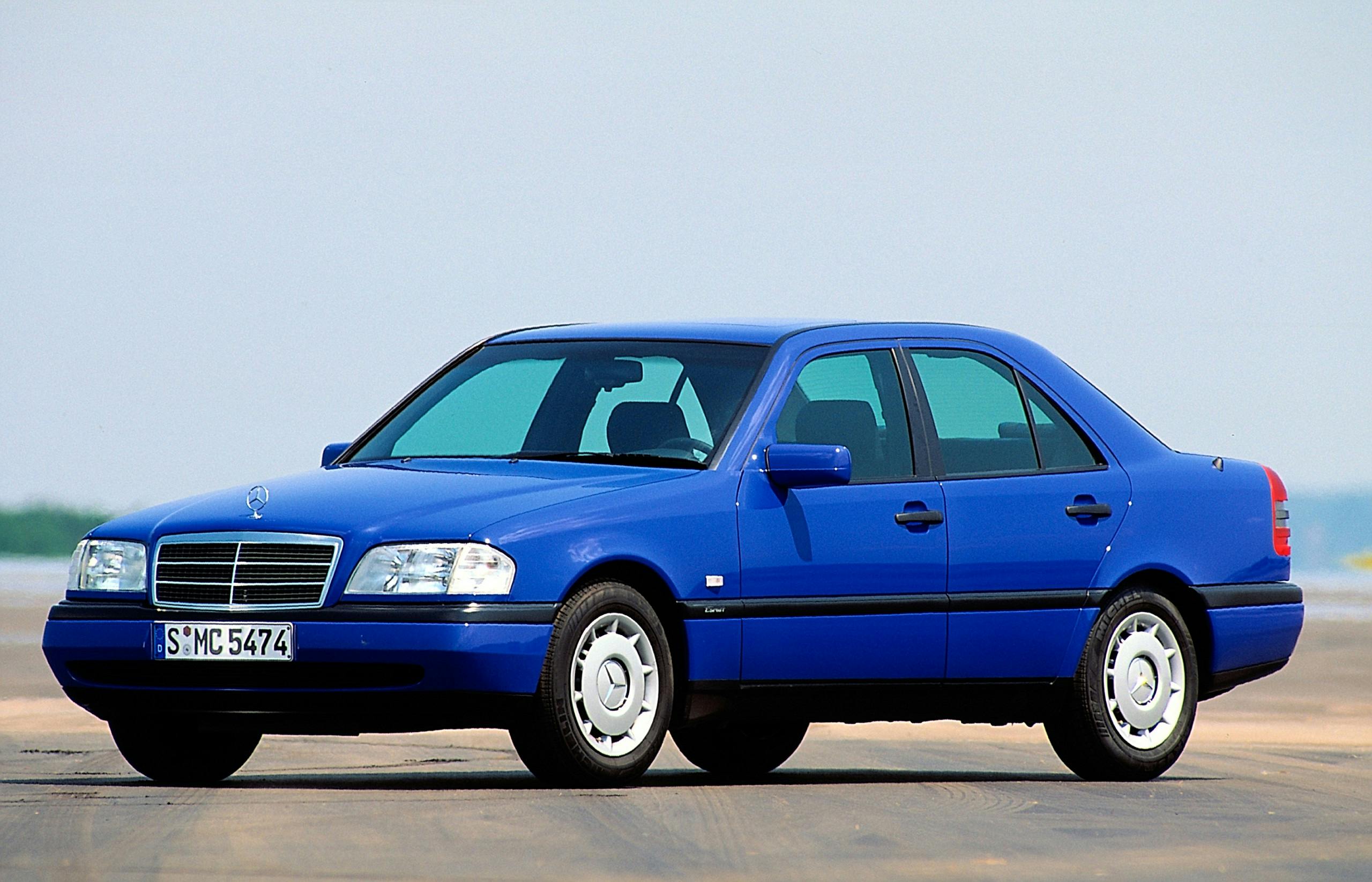 Blauer, klassischer Mercedes-Benz Limousine parkt auf einer Straße bei Tageslicht, Ansicht von vorne links.