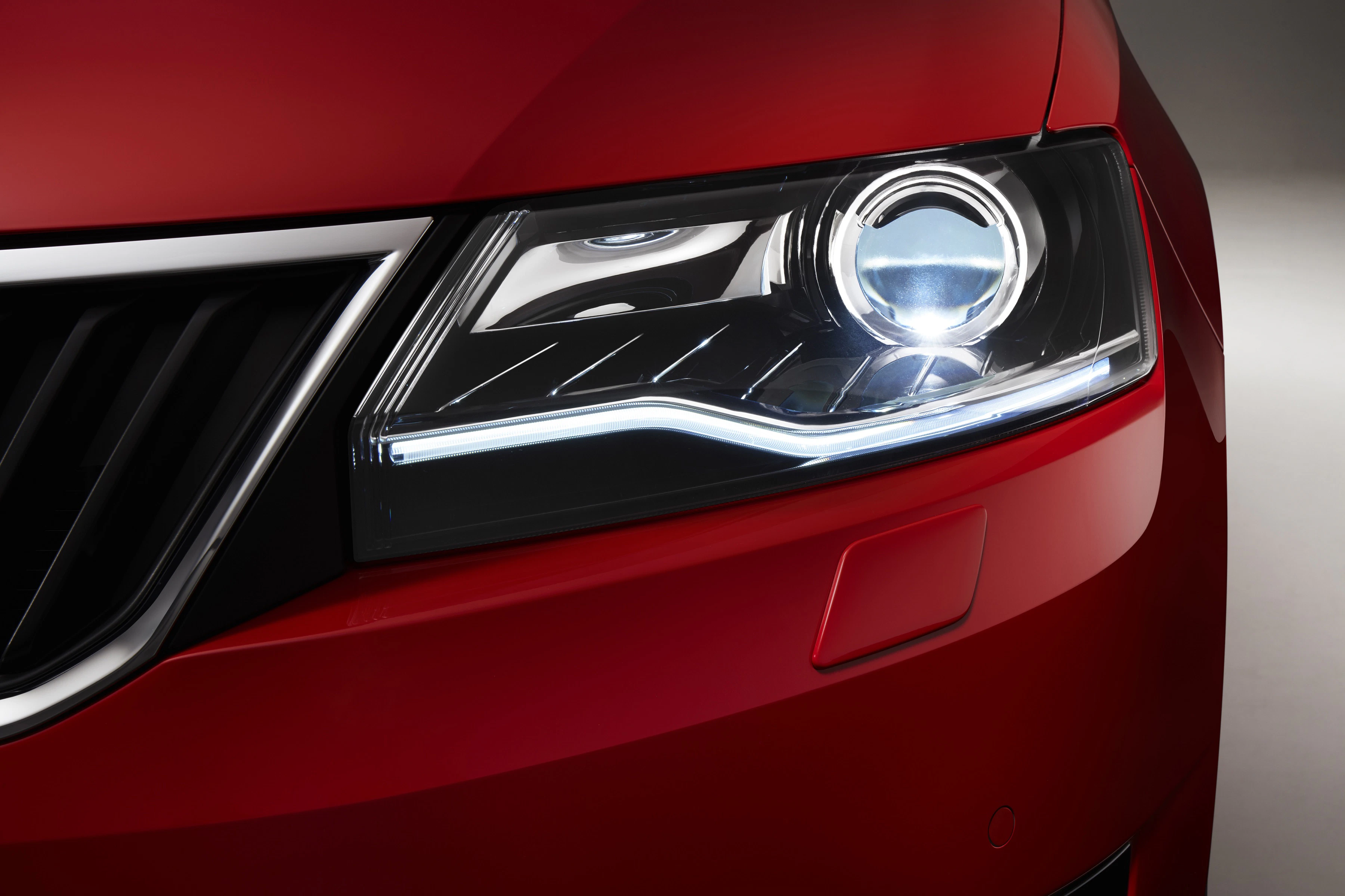 Nahaufnahme eines roten Autoscheinwerfers mit modernen LED-Leuchten und glänzender Karosserie.