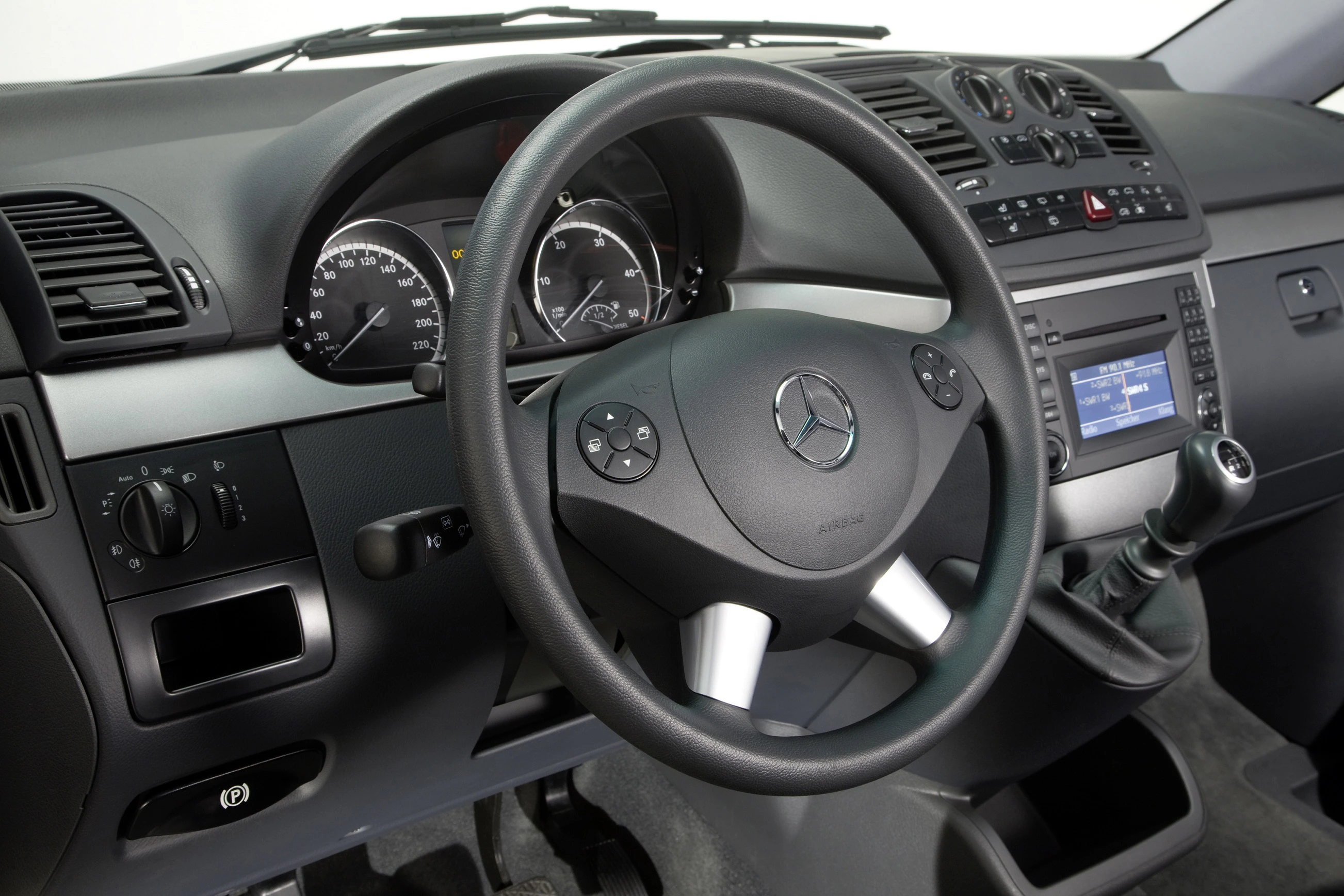 Nahaufnahme eines Mercedes-Innenraums mit Lenkrad, Armaturenbrett und Schalthebel. Modernes Design mit klarer Instrumentenanzeige.