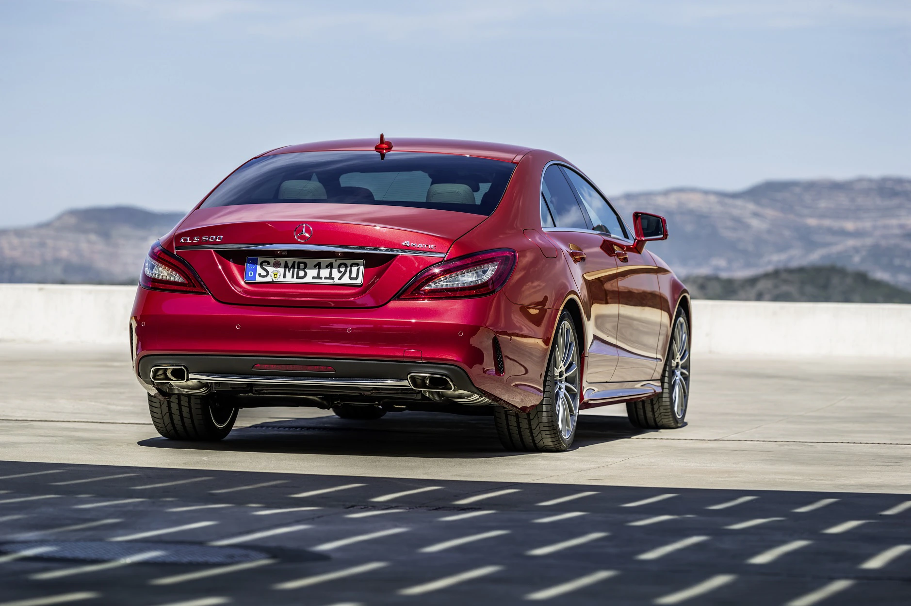 Roter Mercedes-Benz Coupé auf einem Parkplatz mit Bergkulisse im Hintergrund, aufgenommen bei Tageslicht.