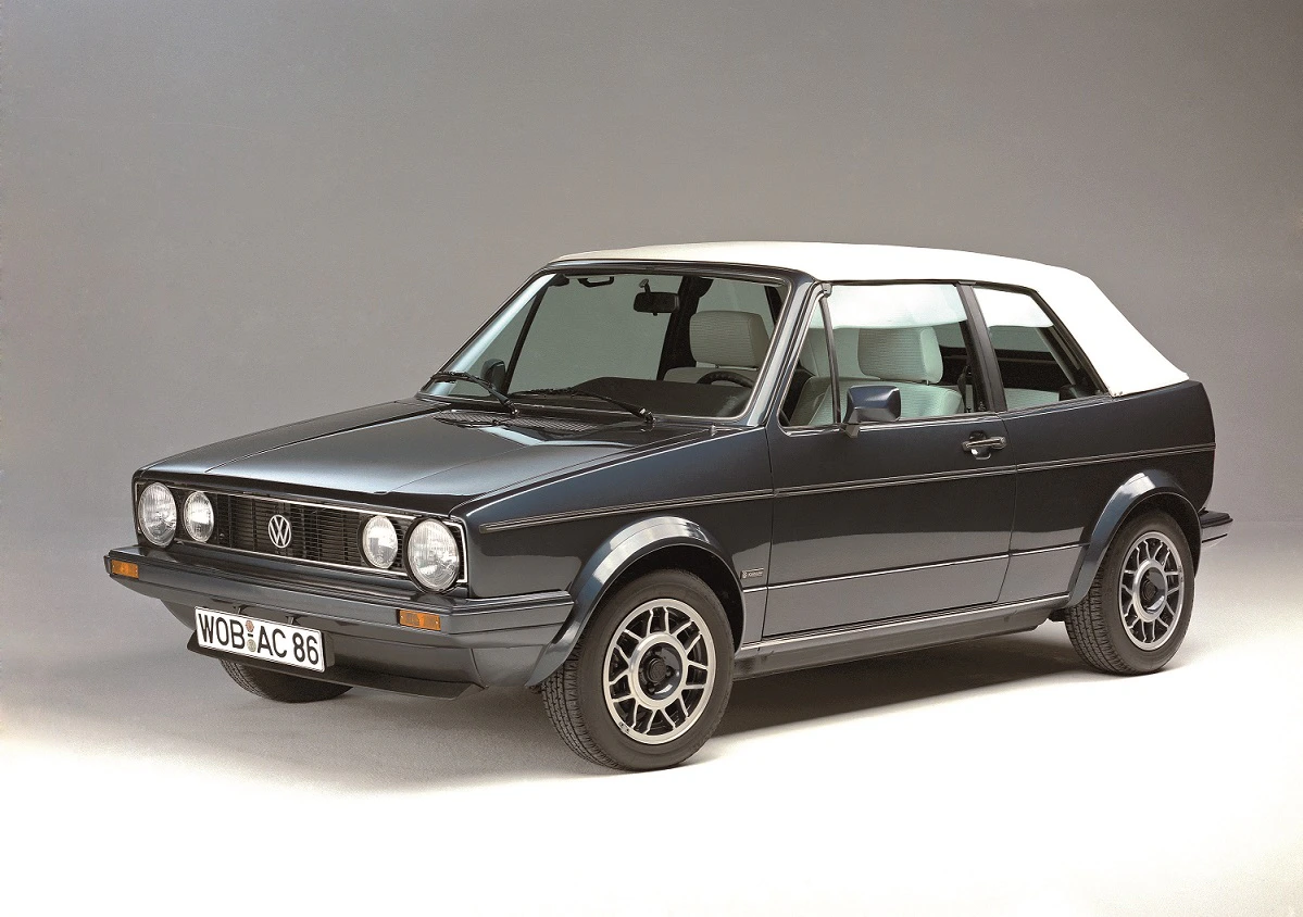 Volkswagen Golf Cabriolet, schwarz, Seitenansicht. Weißes Stoffverdeck und klassische Felgen. Studiohintergrund.