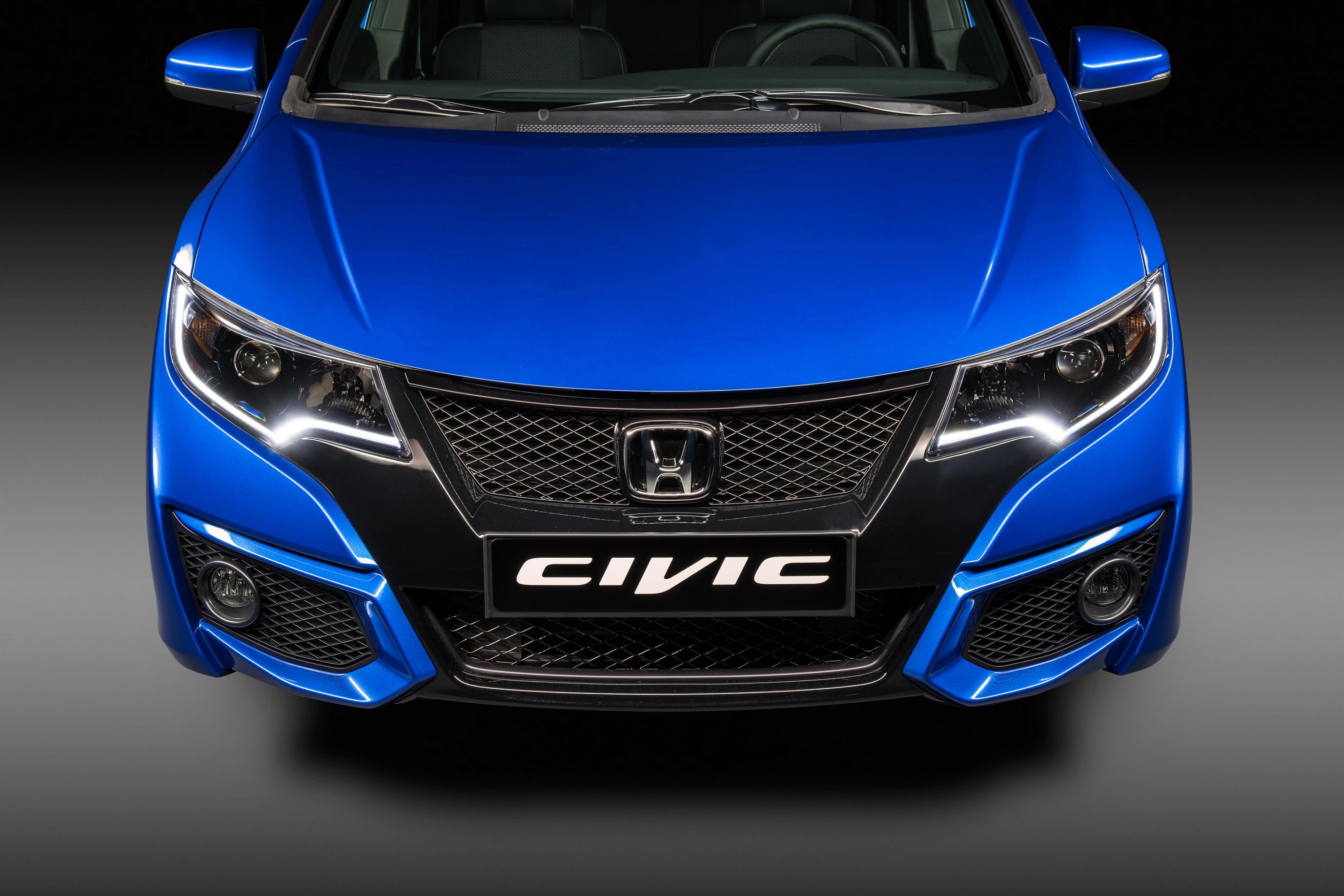 Frontansicht eines blauen Honda Civic mit modernem Design und markanten Scheinwerfern auf schwarzem Hintergrund.