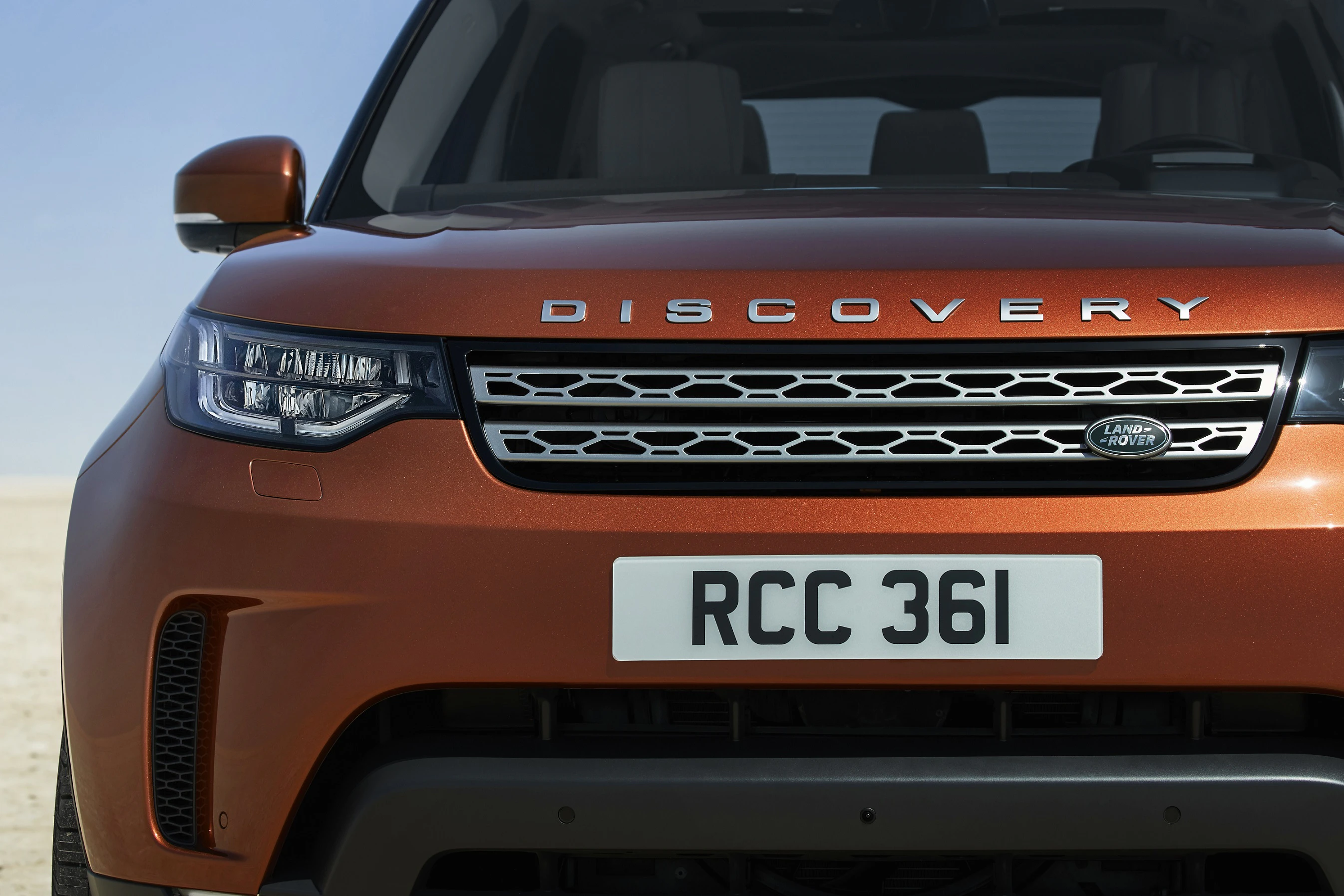 Nahaufnahme eines Land Rover Discovery mit oranger Lackierung und Nummernschild RCC 361 in einer Wüstenlandschaft.