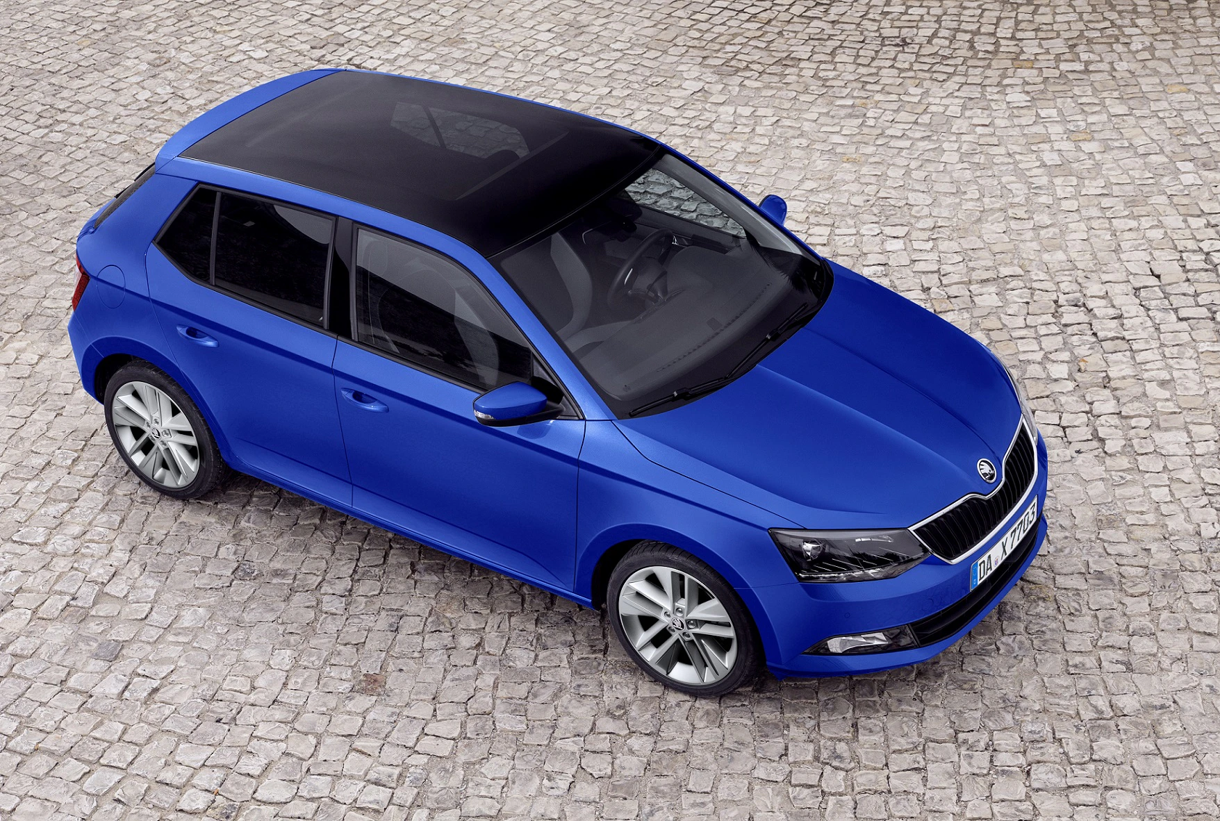 Blauer Škoda Fabia auf Pflastersteinen, aufgenommen aus der Vogelperspektive. Der Wagen hat eine dunkle Panorama-Glasdach.