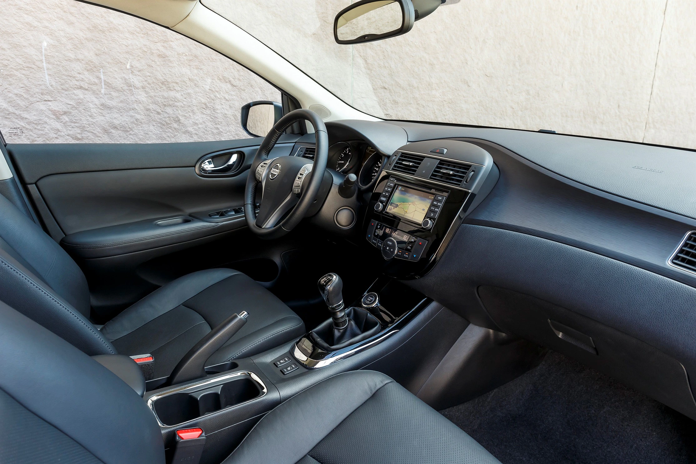 Innenansicht eines Autos mit Lederpolstern. Blick auf Lenkrad, Schalthebel und eingebautem Navigationssystem. Moderne, elegante Gestaltung.