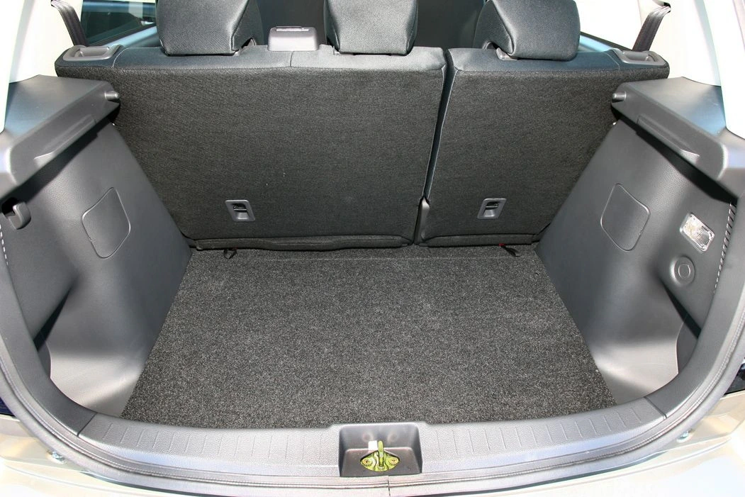 Der Kofferraum eines Autos mit umgeklappten Rücksitzen zeigt einen leeren, sauberen Innenraum mit grauem Teppichboden.