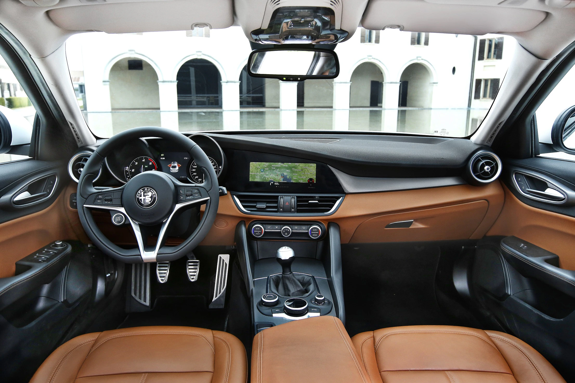 Innenraum eines Autos mit braunen Ledersitzen, modernem Armaturenbrett, Lenkrad und zentralem Bildschirm. Elegantes Design.