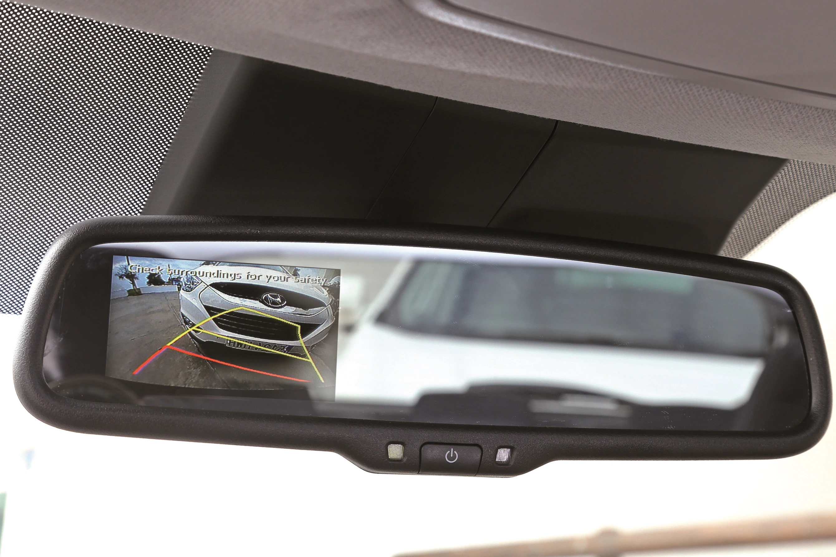 Rückspiegel mit integriertem Bildschirm zeigt Rückfahrkamera-Ansicht eines Autos, mit Sicherheitslinien zur Unterstützung beim Einparken.
