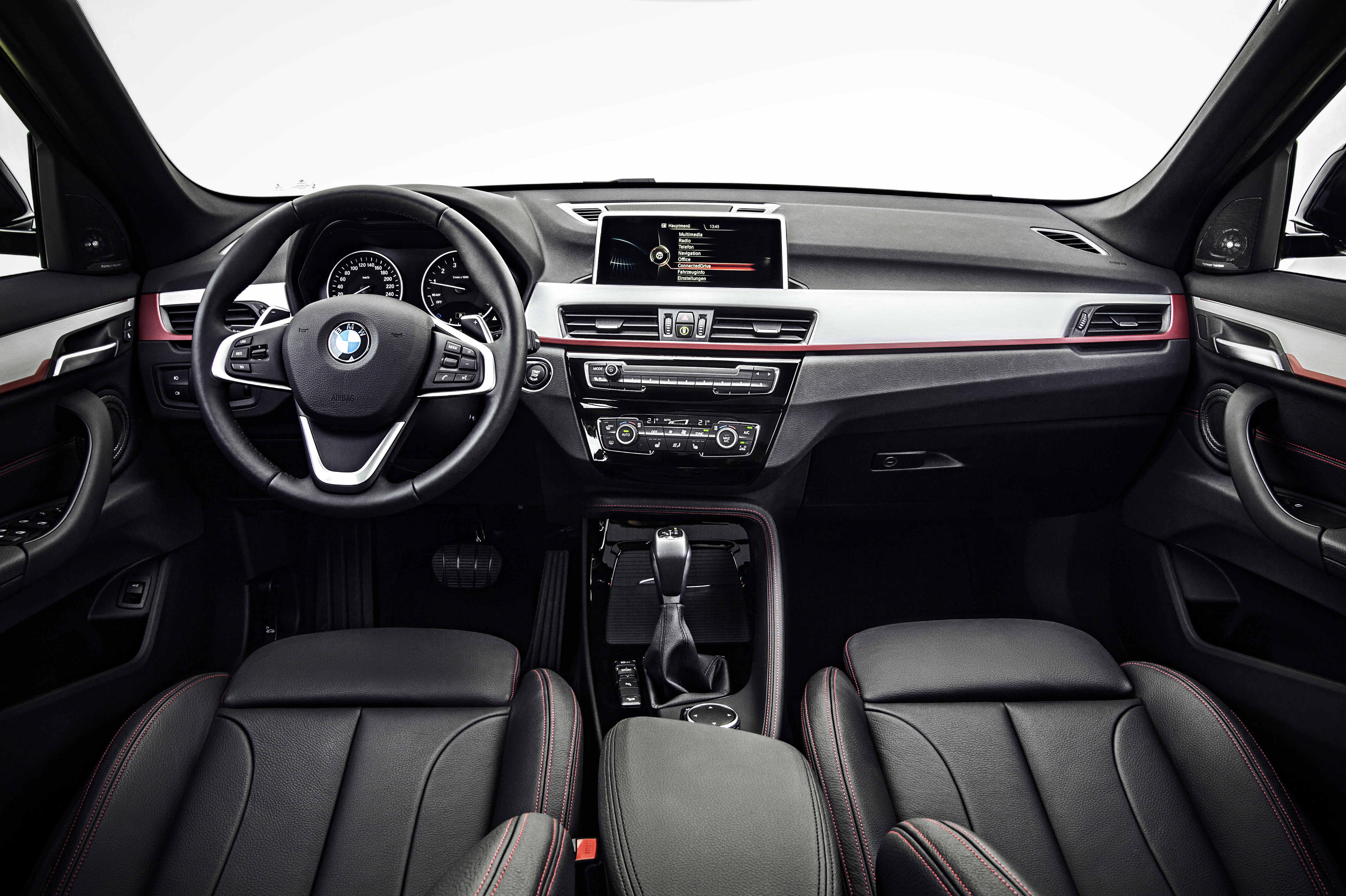 Innenraum eines modernen BMWs mit schwarzer Lederausstattung, Lenkrad, Armaturenbrett und zentralem Display.