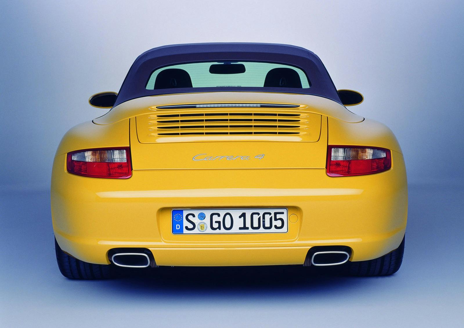 Gelber Sportwagen von hinten mit einem schwarzen Verdeck und Doppelrohrauspuff, vor einem blauen Hintergrund.