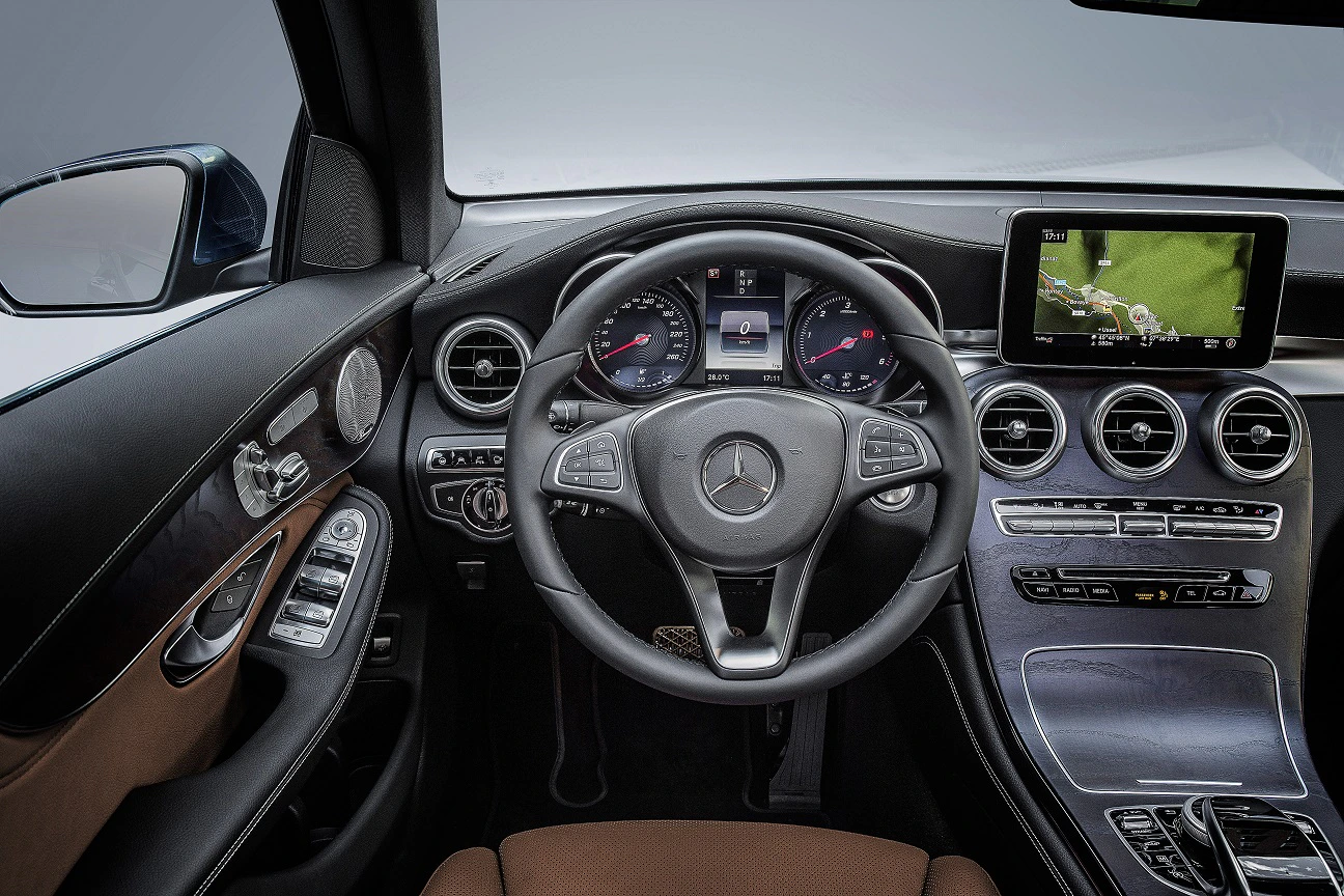 Innenraum eines Mercedes-Benz: Lenkrad, Armaturenbrett mit Touchscreen, Tachometer und Bedienelemente in luxuriösem Design.