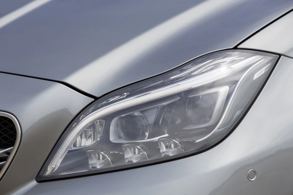Nahaufnahme eines Scheinwerfers eines silbernen Autos mit modernen LED-Elementen, glatt poliertem Lack und dynamischem Design.