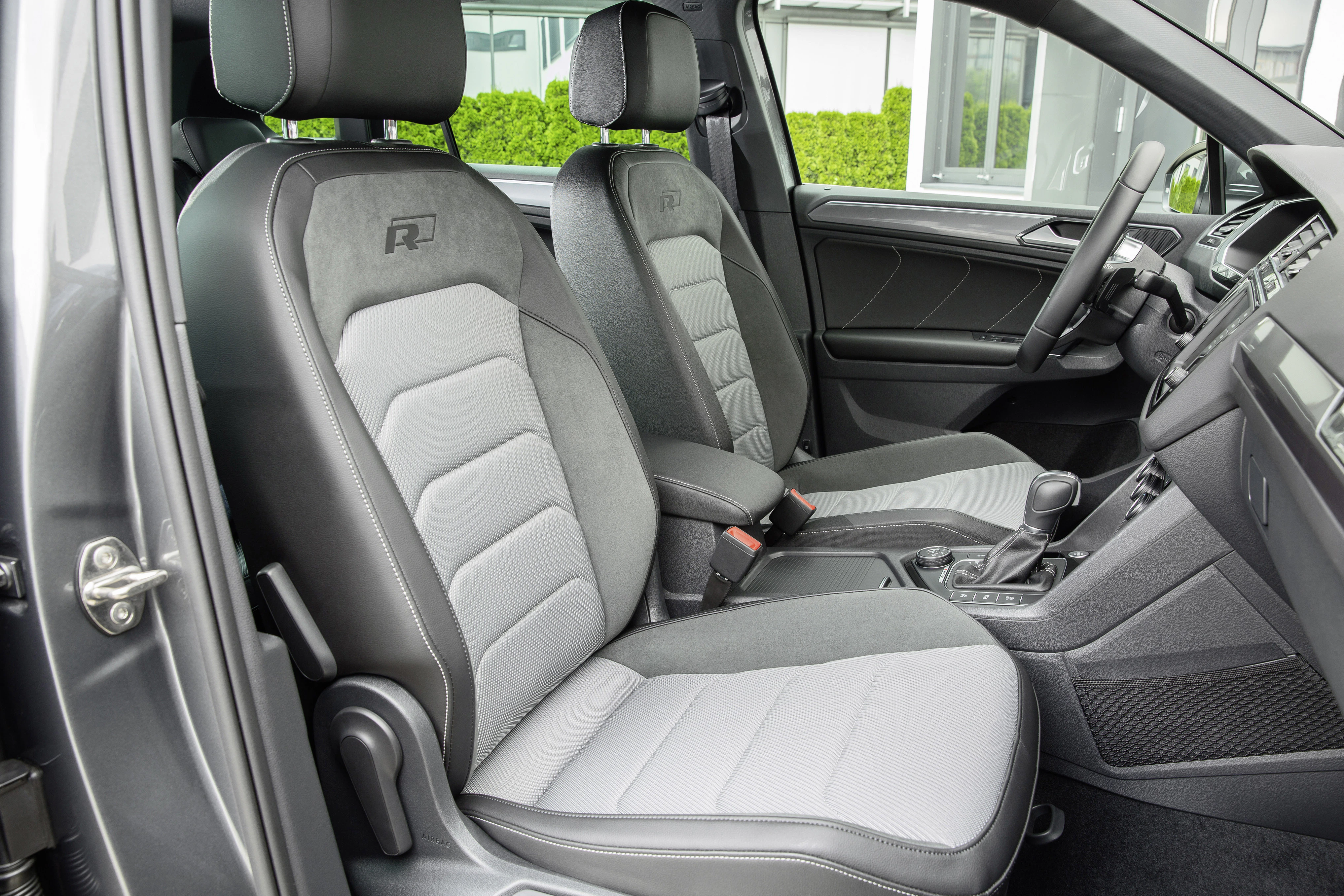Innenraum eines modernen Autos mit grauen Sitzen und schwarzer Verkleidung, gut sichtbar sind Lenkrad und Schaltknüppel.