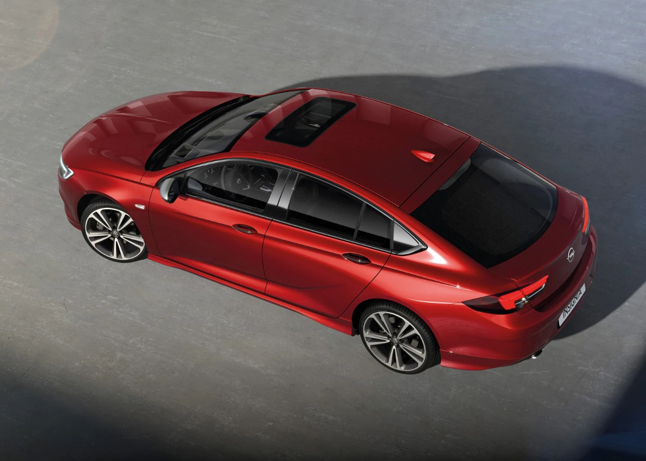 Rotes Auto mit sportlichem Design, Schiebedach und schwarzen Felgen, von oben fotografiert auf grauem Untergrund.