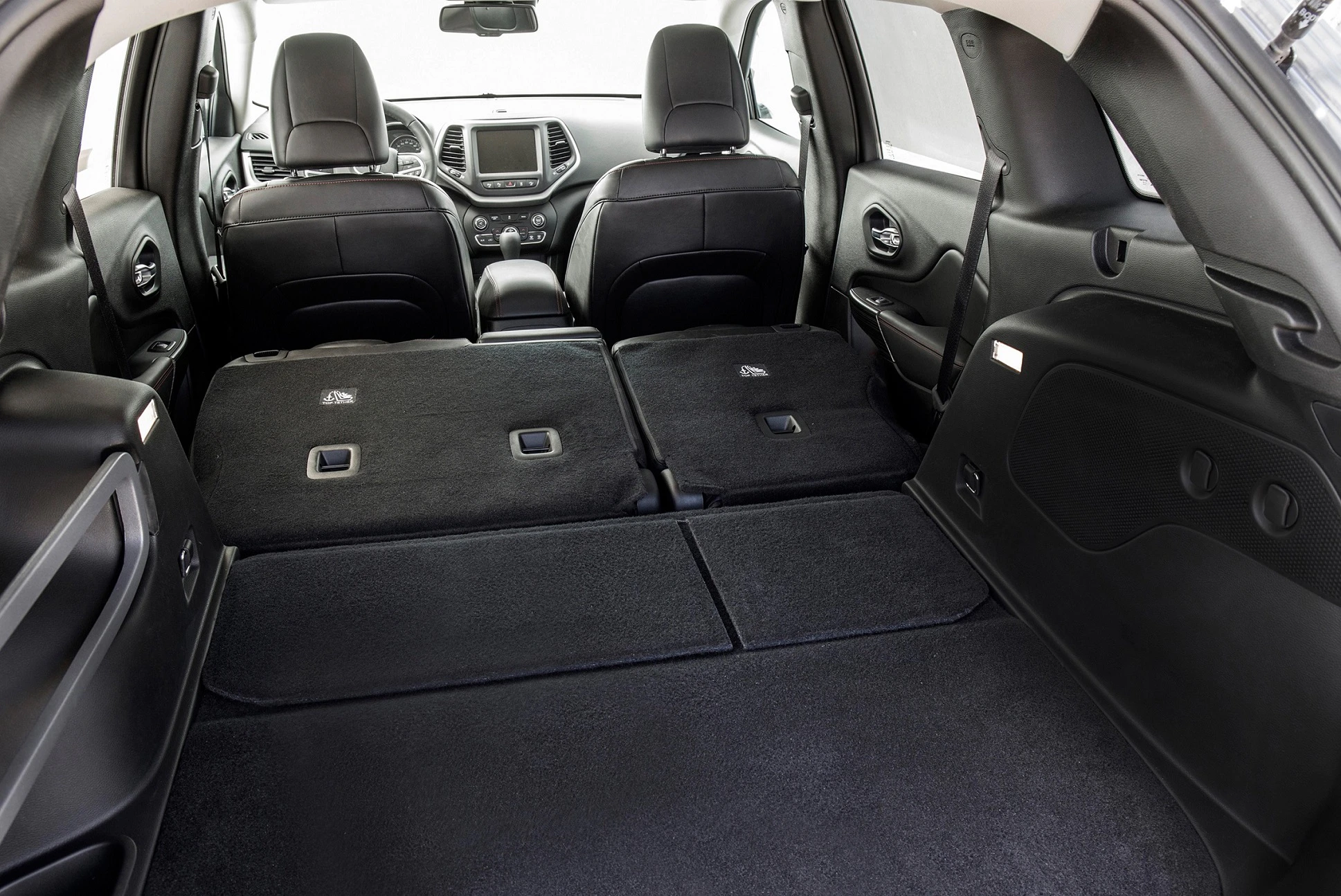 Kofferraumansicht eines Autos mit umgeklappten Rücksitzen, schwarzer Innenraum und Blick auf das Armaturenbrett von hinten.