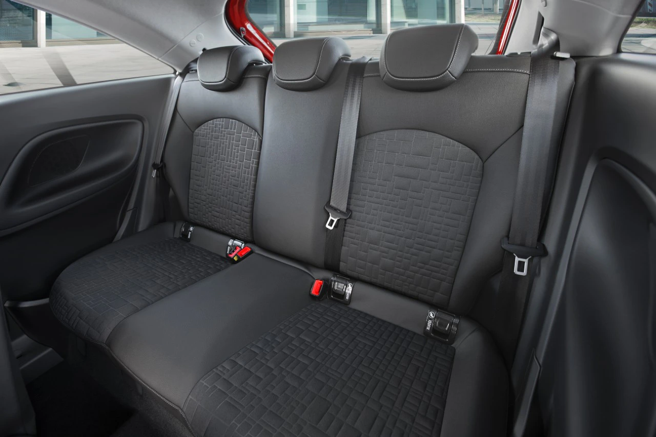 Rückbank eines Autos mit schwarzer Polsterung und drei Sitzen. Sicherheitsgurte sind sichtbar. Hintergrund unscharf.