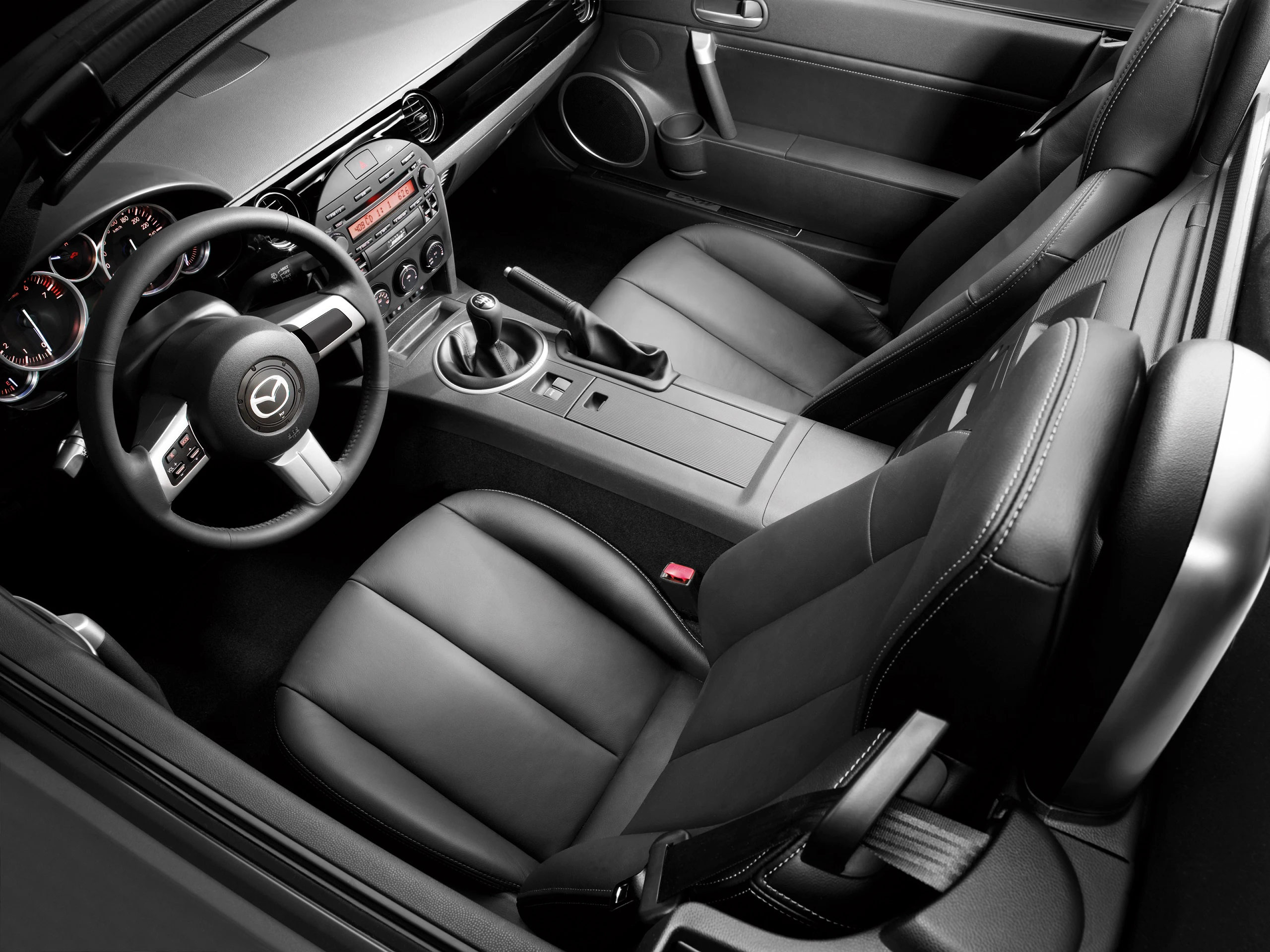 Innenraum eines Autos mit schwarzem Leder, sichtbares Lenkrad und Armaturenbrett, Schalthebel und zwei Vordersitze.