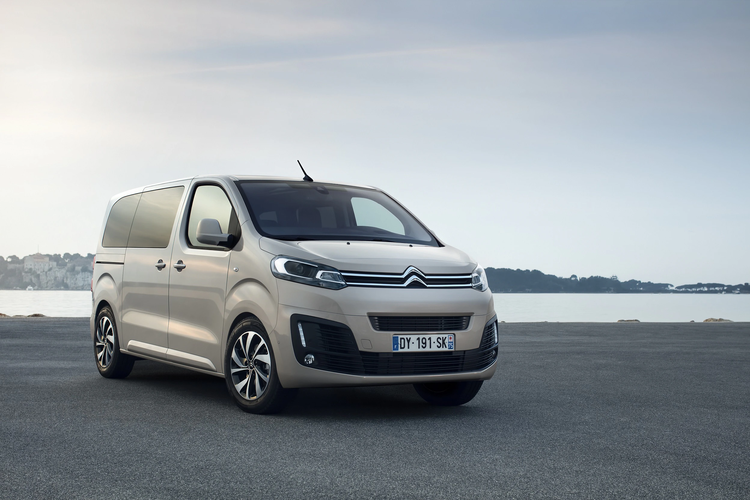 Silberner Citroën Van steht auf einem Parkplatz mit Blick auf ein ruhiges Gewässer bei Tageslicht.
