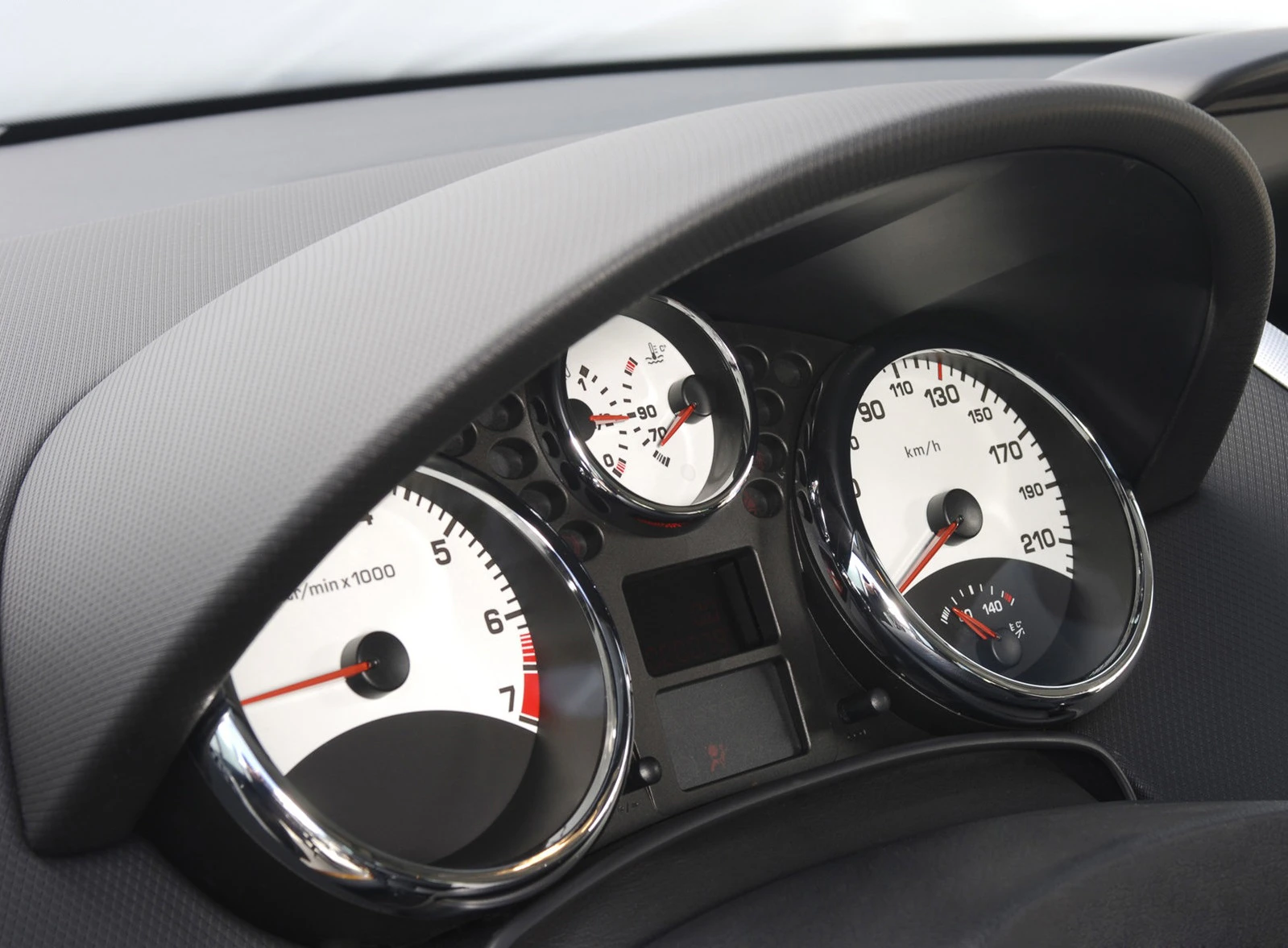 Nahaufnahme eines Auto-Tachometers mit weißen Zifferblättern und Chromrändern. Anzeigen für Geschwindigkeit und Drehzahl sind sichtbar.