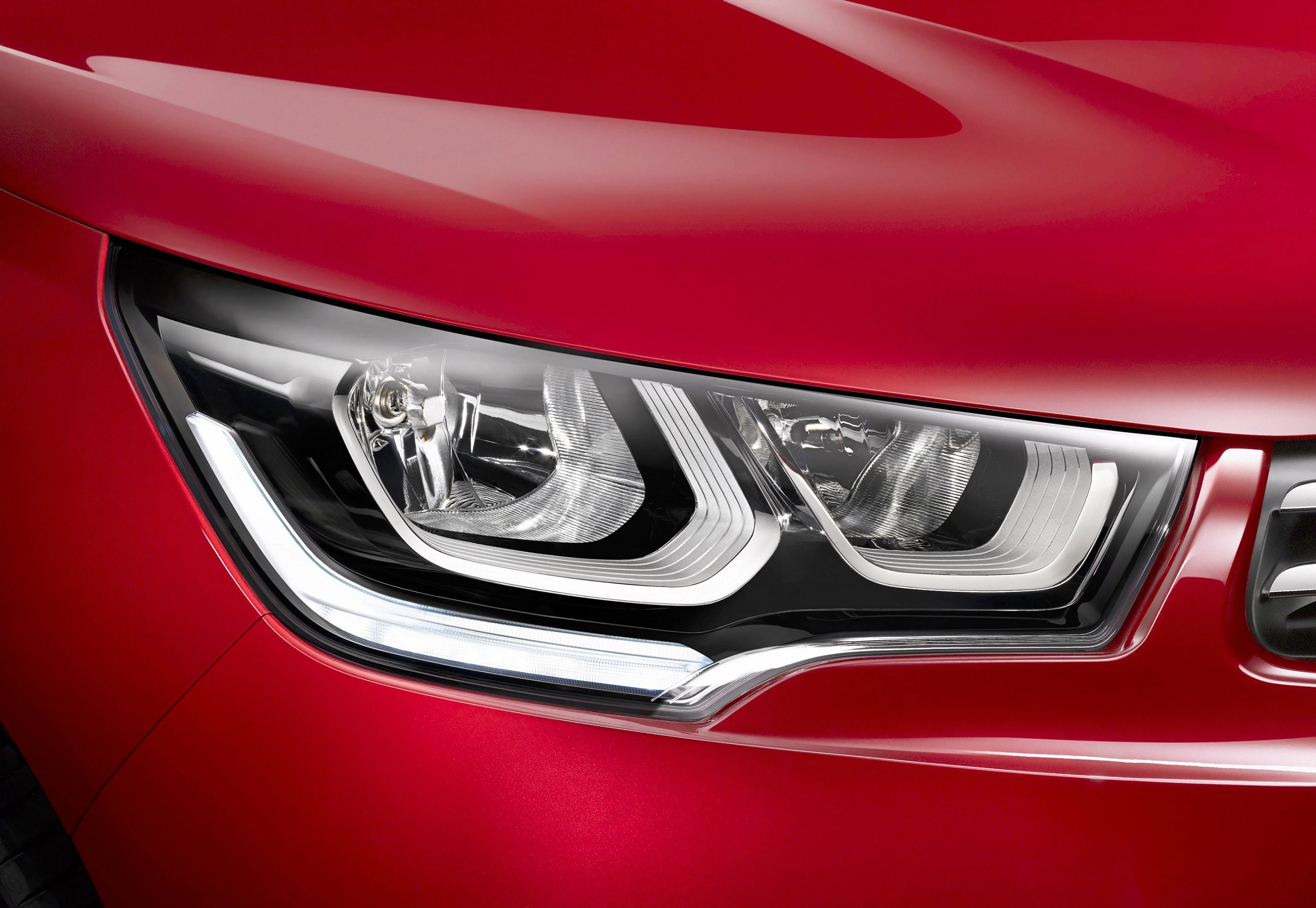Nahaufnahme eines roten Autoscheinwerfers mit modernen, stilisierten LED-Lichtern und glänzender Lackierung.