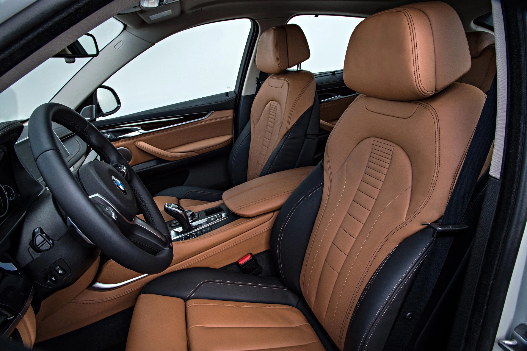 Innenraum eines Autos mit braunen Ledersitzen und modernem Armaturenbrett. Automatikgetriebe und multifunktionales Lenkrad sind sichtbar.
