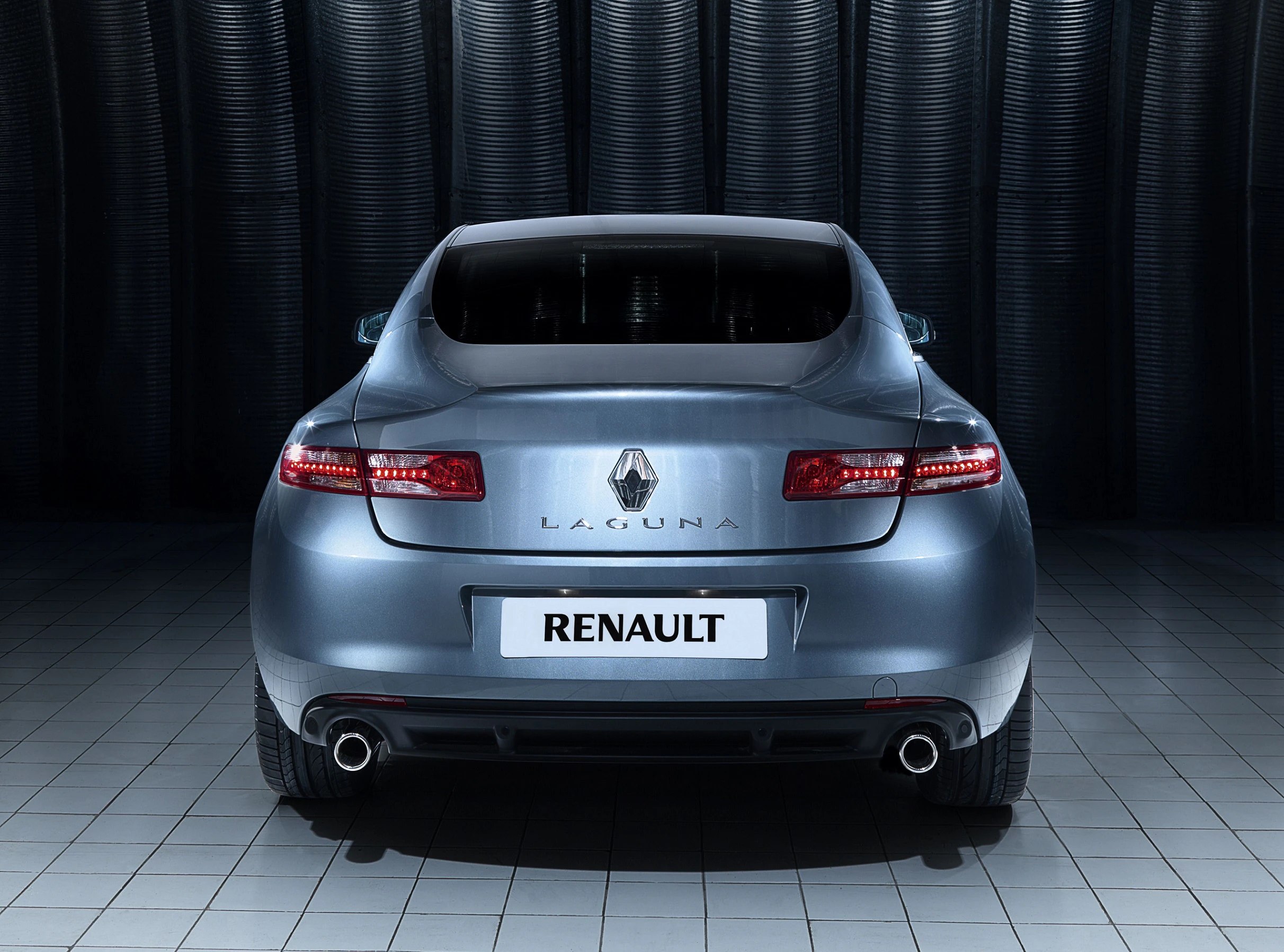 Ein silberner Renault Laguna steht in einer dunklen Garage. Rückansicht mit hervorgehobenen Rücklichtern und Doppelrohrauspuff.
