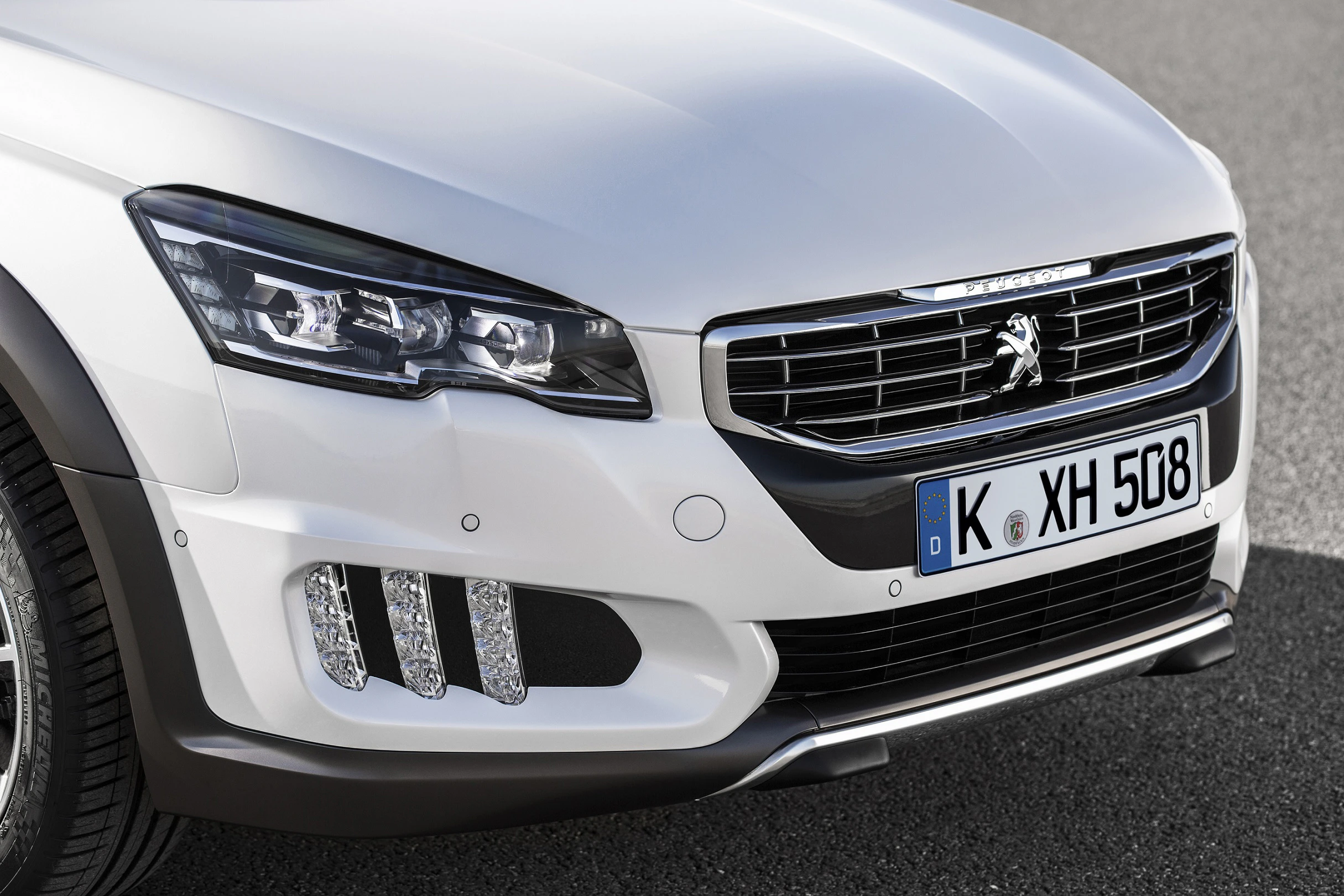 Nahaufnahme eines weißen Peugeot mit deutschem Kennzeichen. Vorderansicht mit markantem Kühlergrill und moderner Scheinwerfergestaltung.