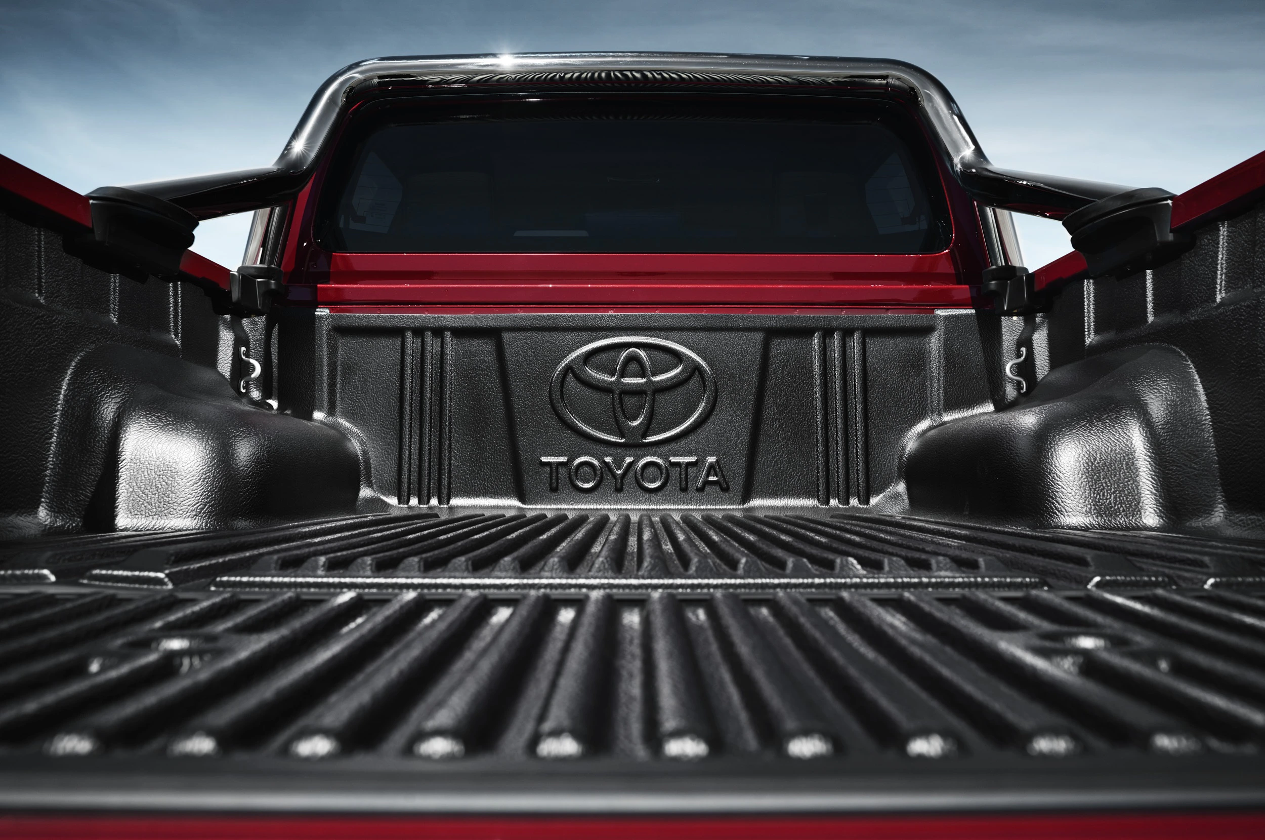 Rote Toyota-Pickup-Ladefläche aus schwarzem Kunststoff, fotografiert von innen. Klarer Himmel im Hintergrund.