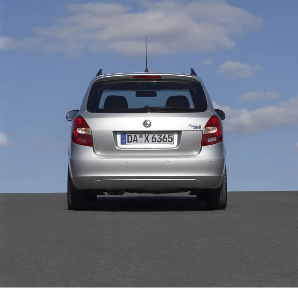 Silberner Skoda Fabia von hinten auf einer Straße, unter blauem Himmel mit ein paar Wolken.