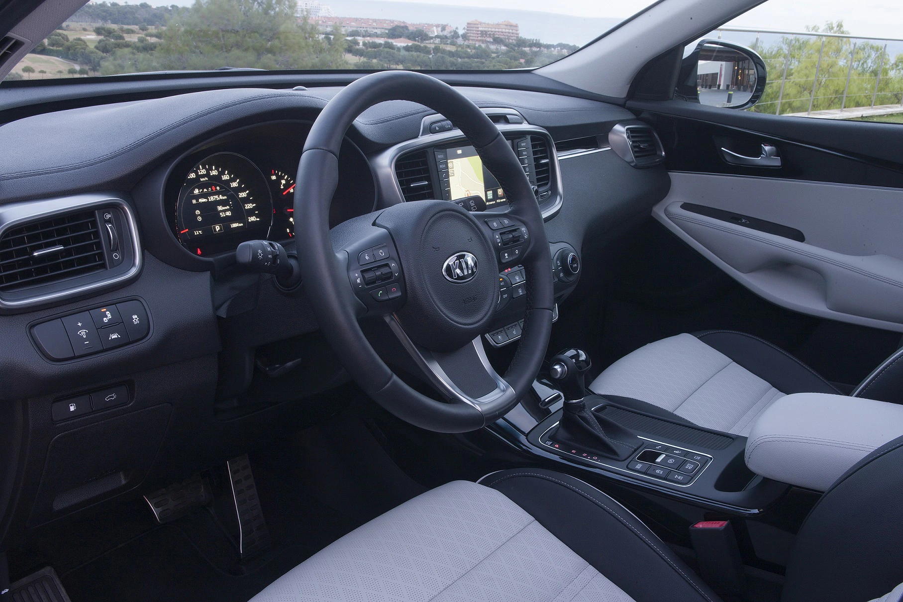 Innenansicht eines Autos mit modernem Armaturenbrett, Lenkrad, Tachometer und Mittelkonsole. Helle und dunkle Polsterkombinationen.