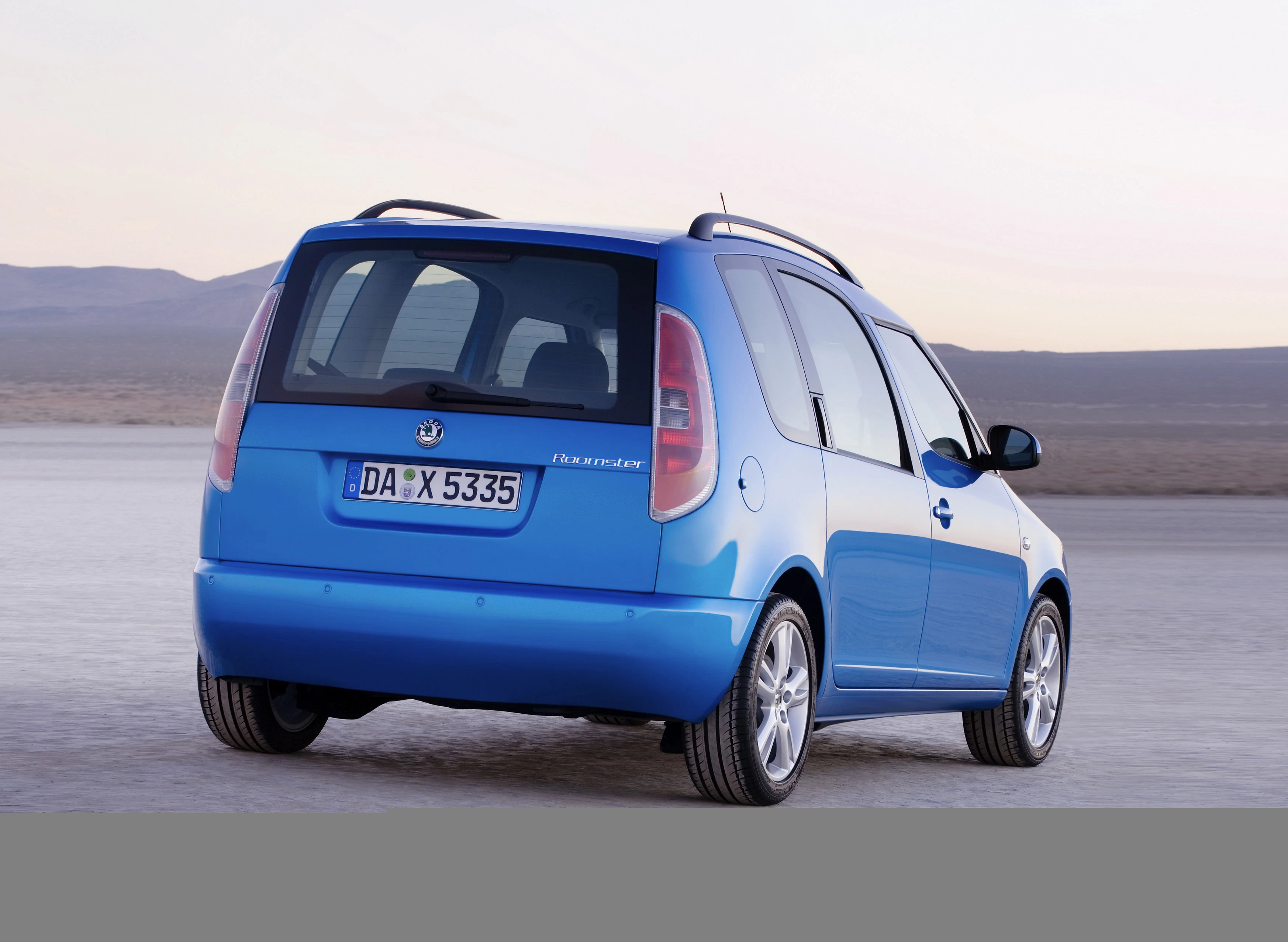 Blauer Skoda Fabia Kombi auf einer weiten, hellen Fläche mit Horizont; Rückansicht, Nummernschild sichtbar.