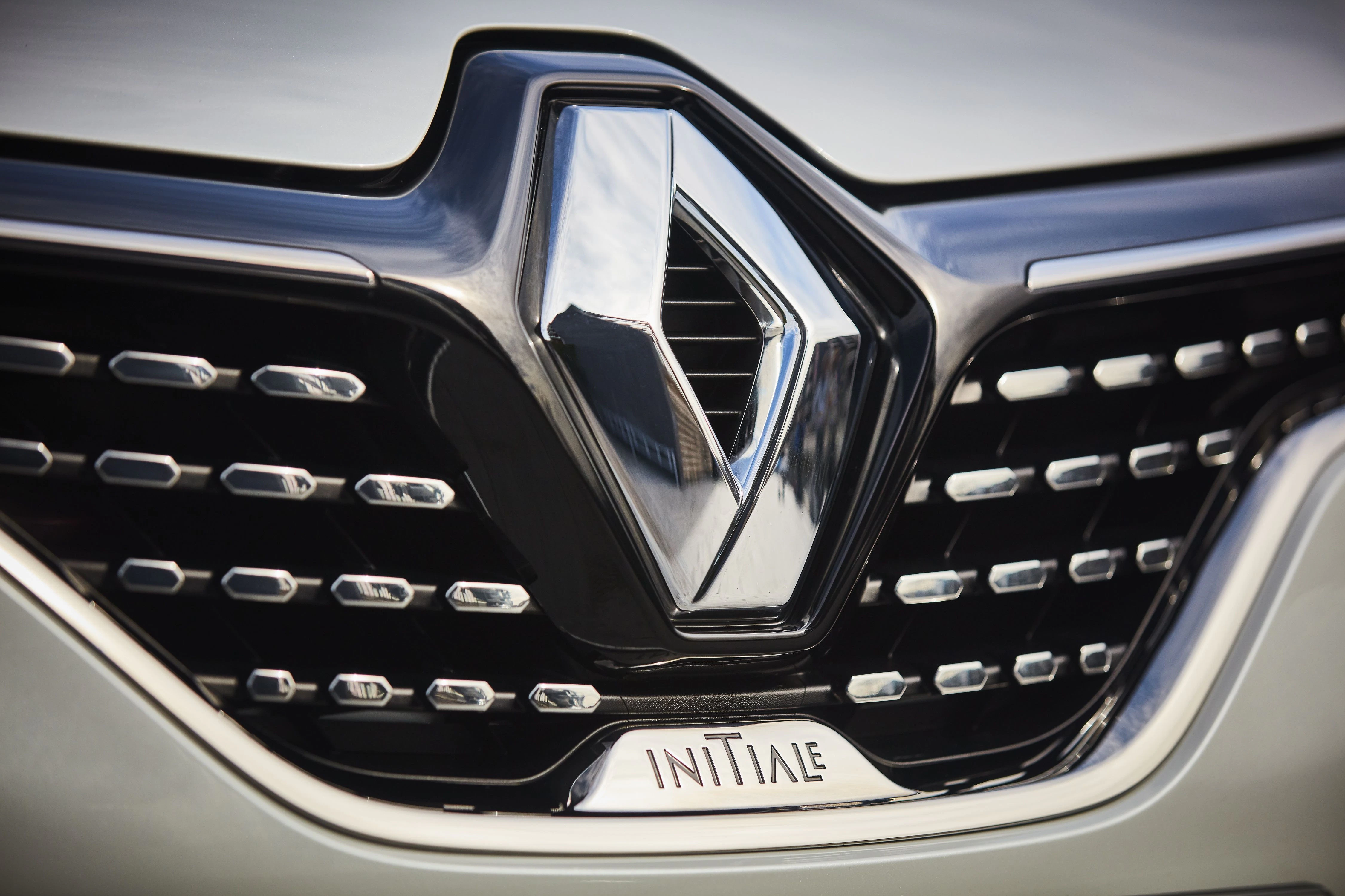 Nahaufnahme eines Renault-Autogrills mit markentypischem Logo und Chromelementen. Darunter der Schriftzug "INITIALE".