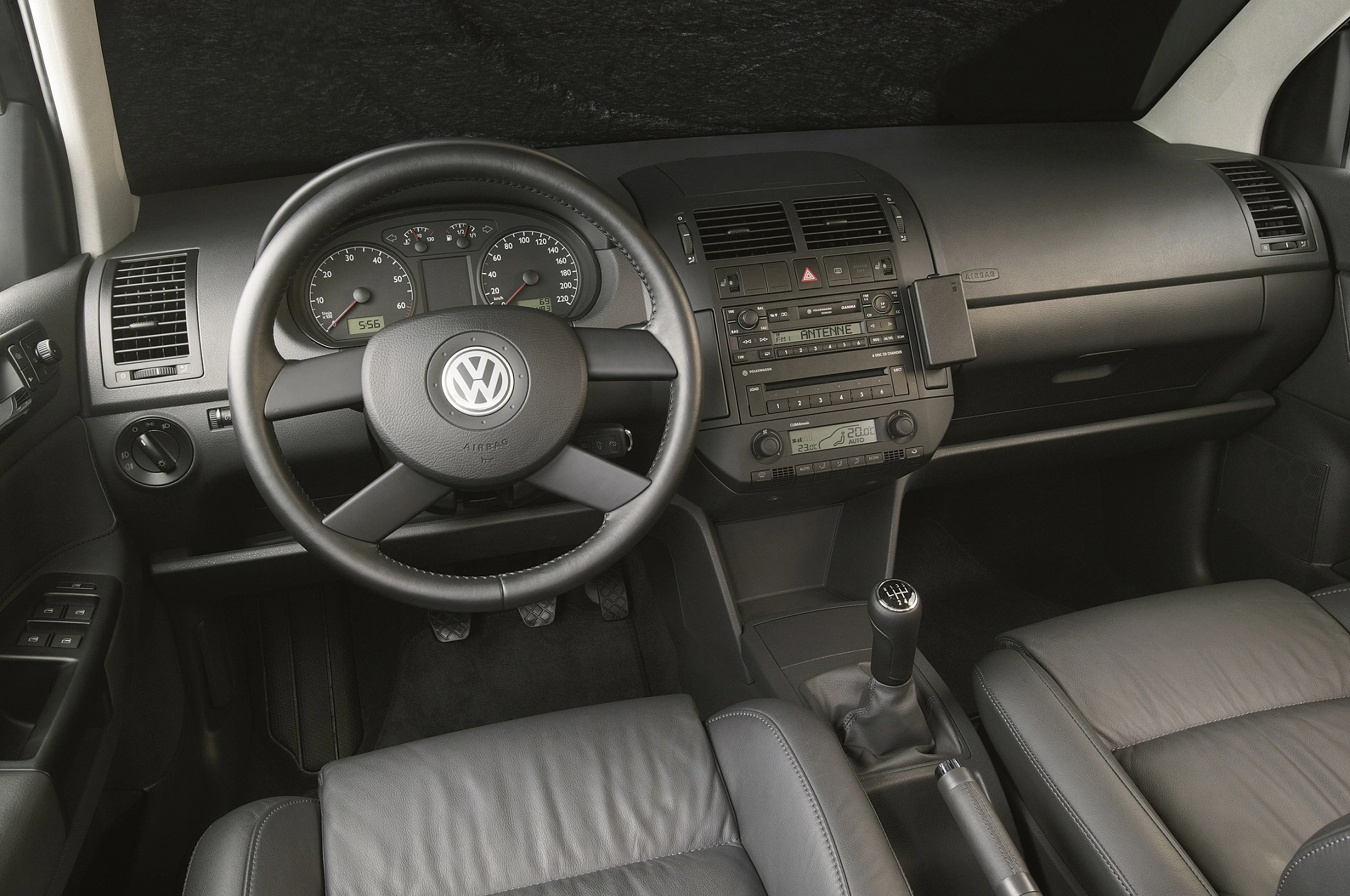 Innenraum eines Autos mit schwarzem Armaturenbrett, Volkswagen-Lenkrad, Instrumentenanzeige, Mittelkonsole und Schalthebel.