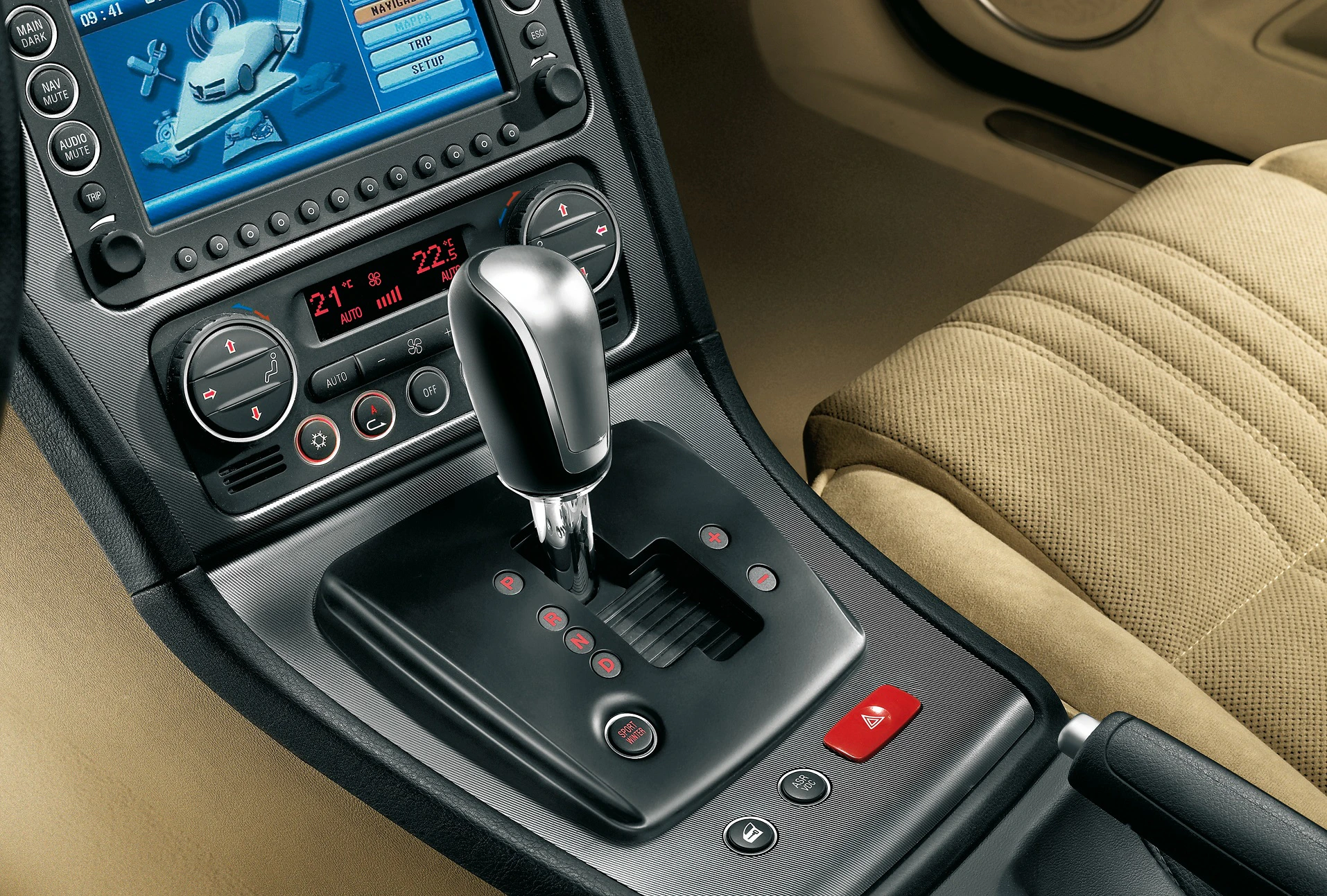 Nahaufnahme eines Automatikgetriebes in einem Auto. Der Schalthebel ist von Bedientasten umgeben, das Display zeigt Navigationselemente.