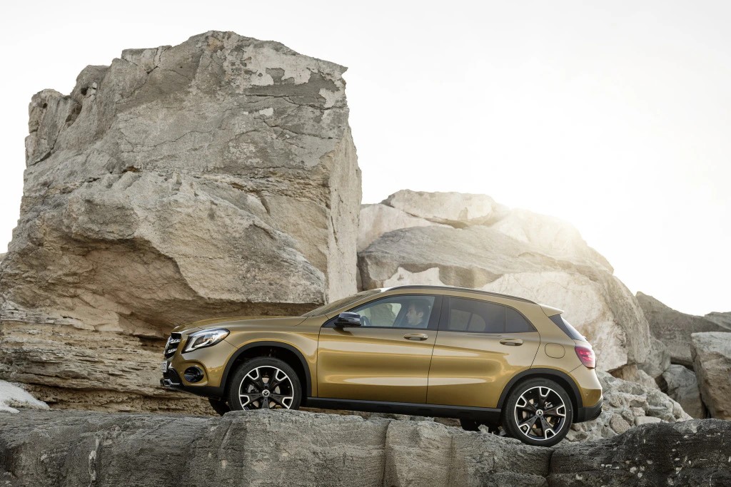 Goldener SUV parkt auf Felsenlandschaft, umgeben von großen, hellen Felsformationen unter klarem Himmel.